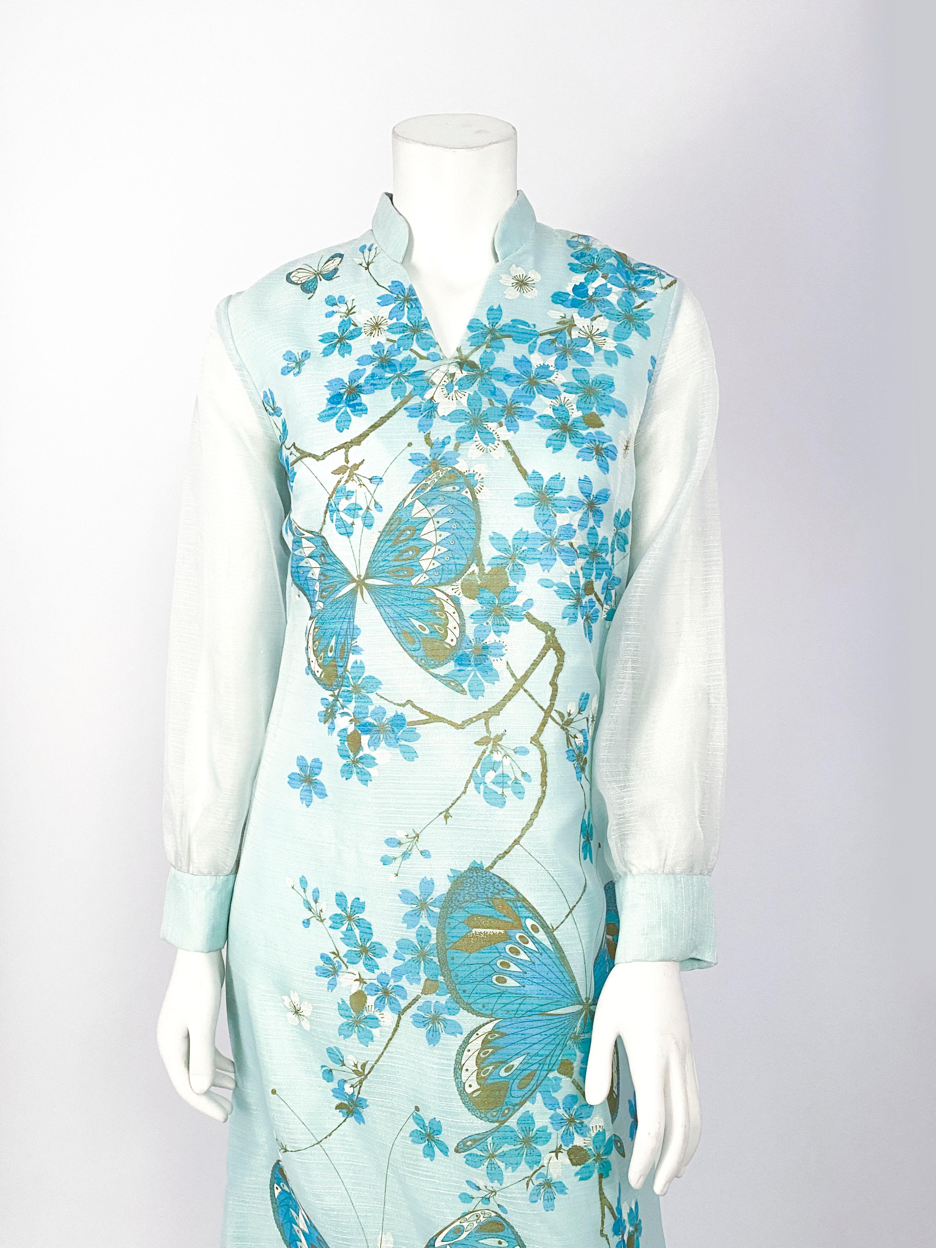 1970s Alfred Shaheen aqua blue Hawaiian painted full-length dress featuring enlarged butterfly motifs. The shift silhouette is finished with a Mandarin neckline and sheer long cuffed sleeves.