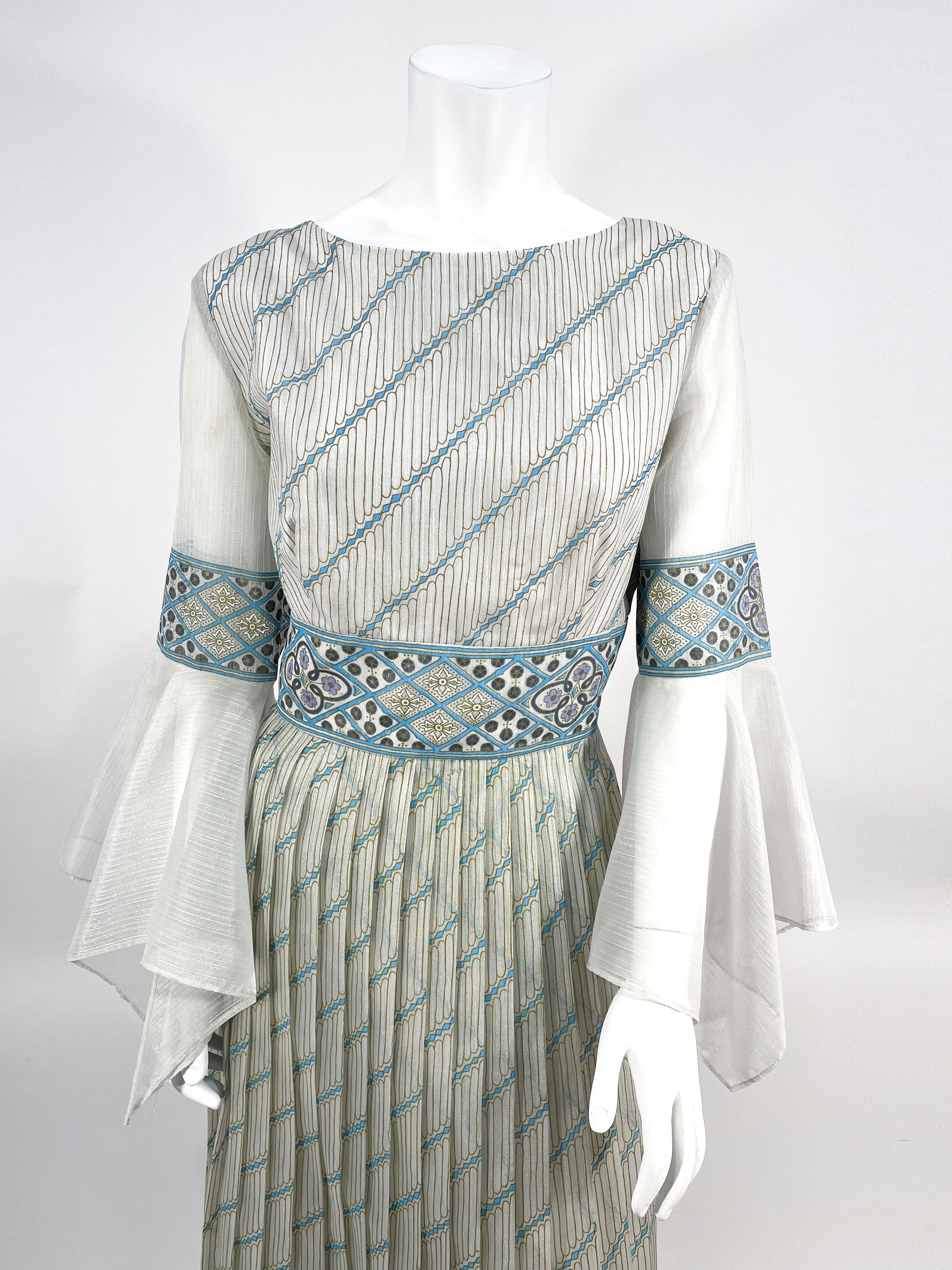 1970s Alfred Shaheen printed organza dress featuring an abstract, floral, and geographic motif in shades of sea foam blue, turquoise, olive and white. The sheer unsigned sleeves are finished with a wide handkerchief bell sleeve. An intricate boarder