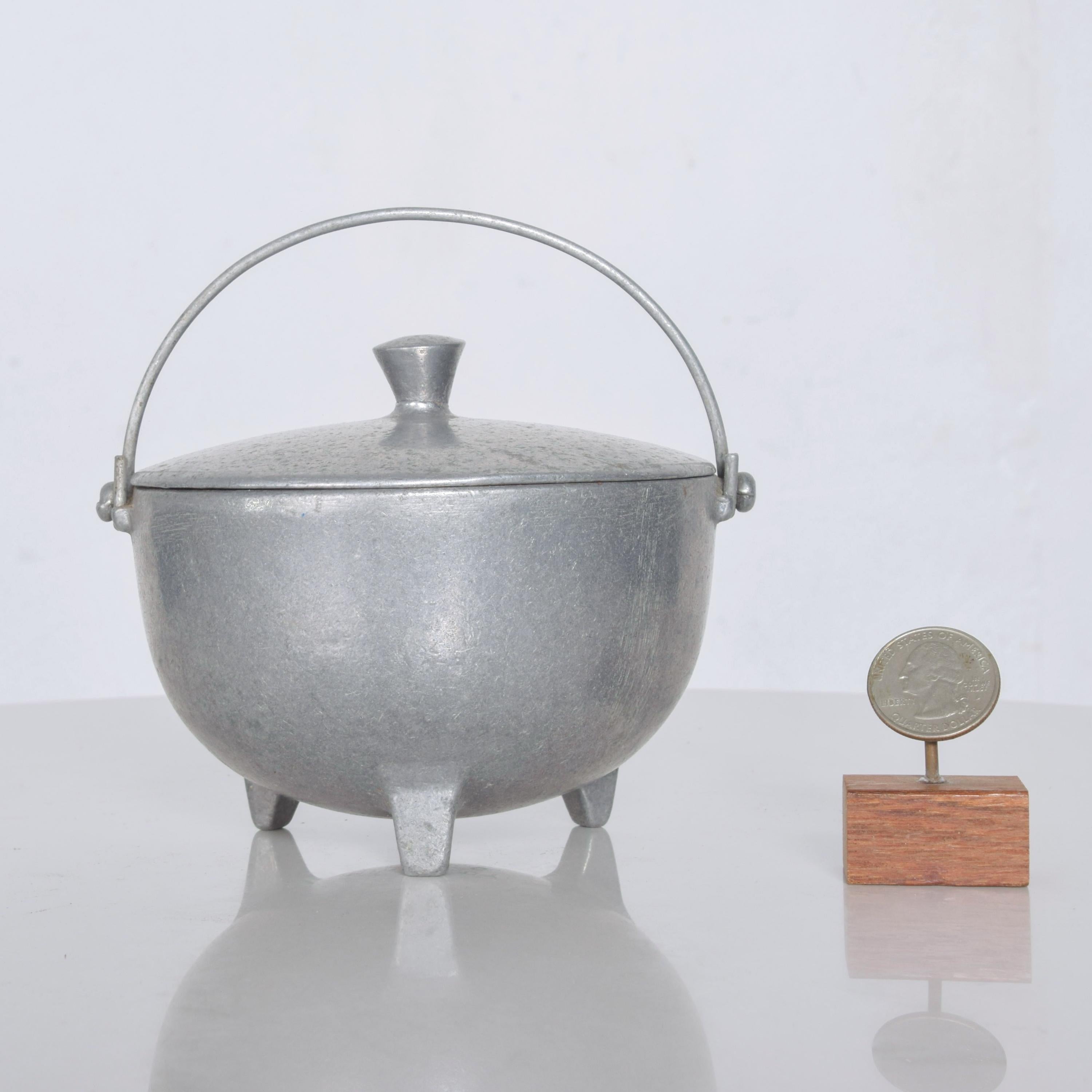 Vintage 1970s solid aluminum footed kettle pot Minalloy NYC
This is an aluminum alloy made to replicate antique pewter.
Sculptural industrial designed hand carry covered lid pot with three leg footed base.
Fantastic industrial decorative