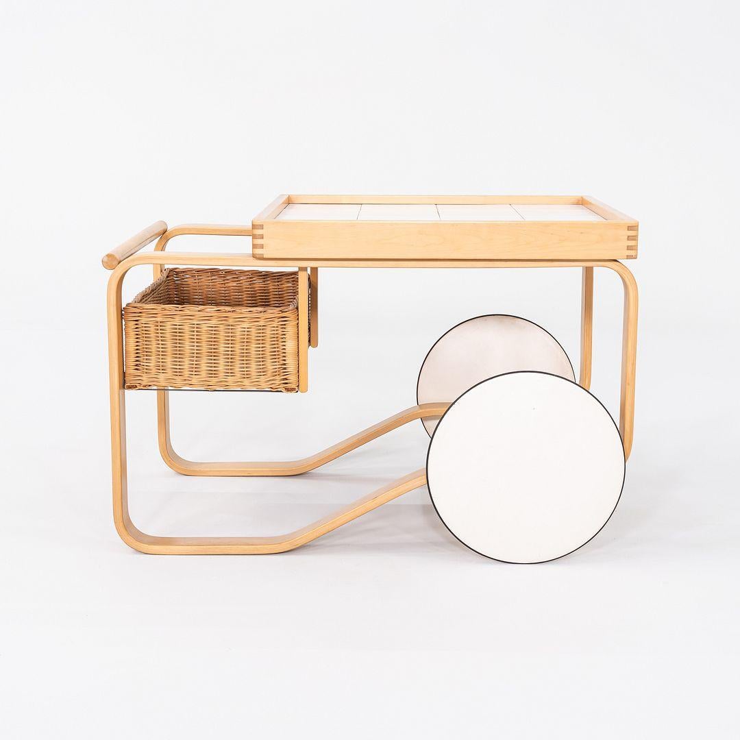 Se trata de un carro de té 900, diseñado originalmente en 1937 por Aino y Alvar Aalto para la Exposición Universal de París. El carrito tiene una encimera de baldosas de cerámica blanca y una cesta de ratán que lo hace perfecto para servir. El