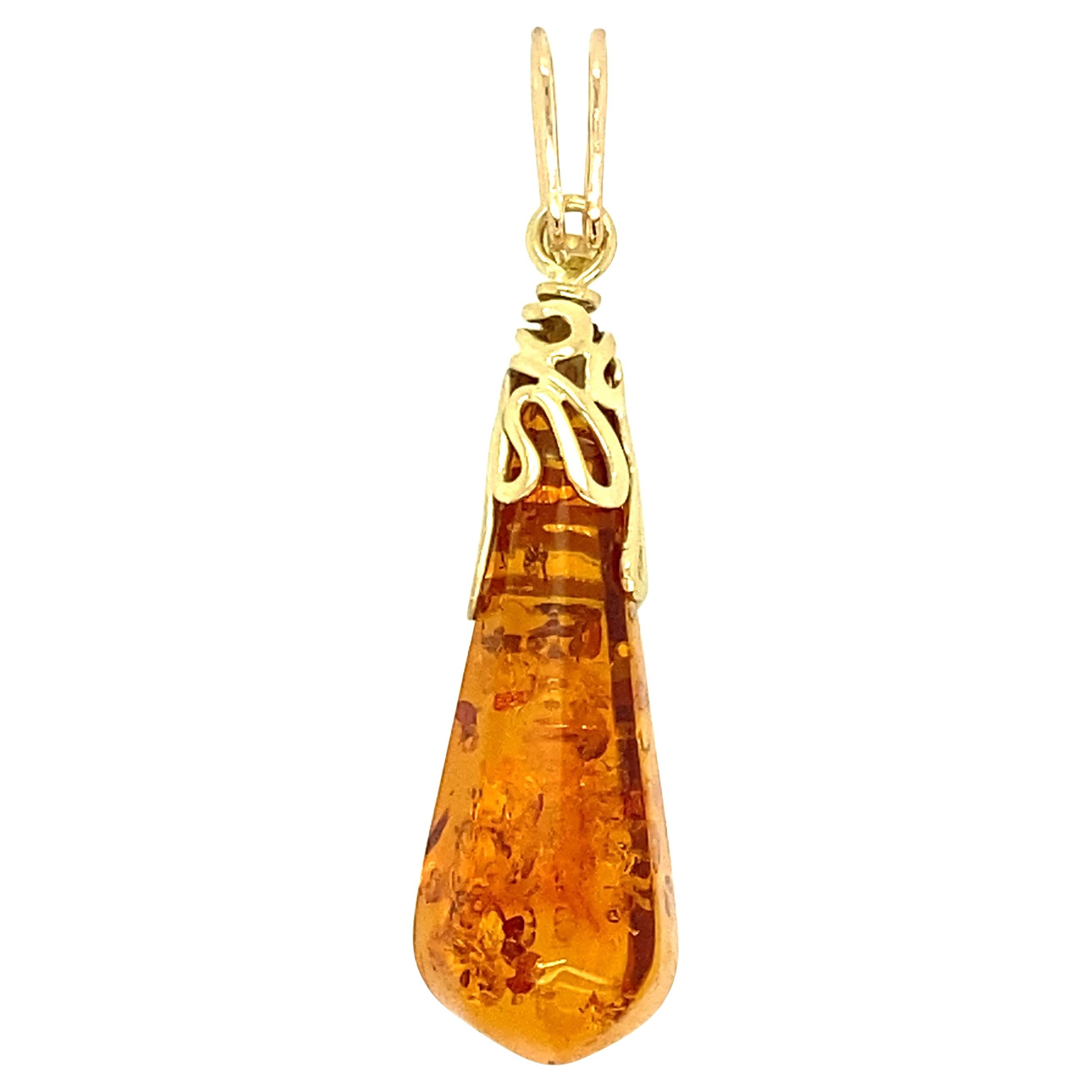 One 14 karat yellow gold amber pendant measuring 1.75 inches in length.  