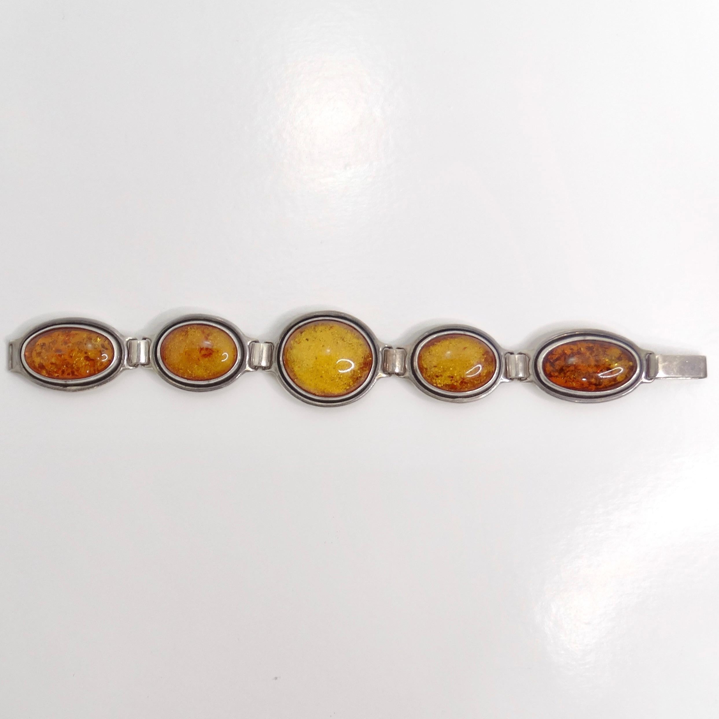 Voici le bracelet en argent et ambre des années 1970, une pièce vintage étonnante qui allie des couleurs vibrantes à un travail artisanal élégant. Ce magnifique bracelet est composé de cinq pierres d'ambre orange, chacune étant sertie de manière