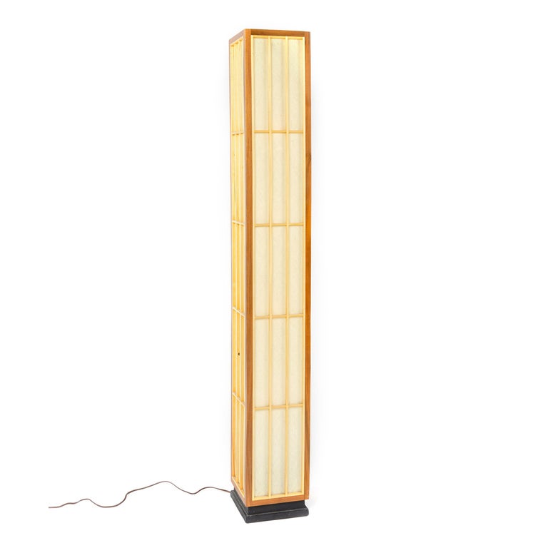 Four sided floor lamp evoking a Japanese Shoji screen. The frame of solid walnut set on an ebonized recessed plinth base with the frame having a grid pattern of solid birch strips framing a translucent fiberglass lining which conceals four Edison