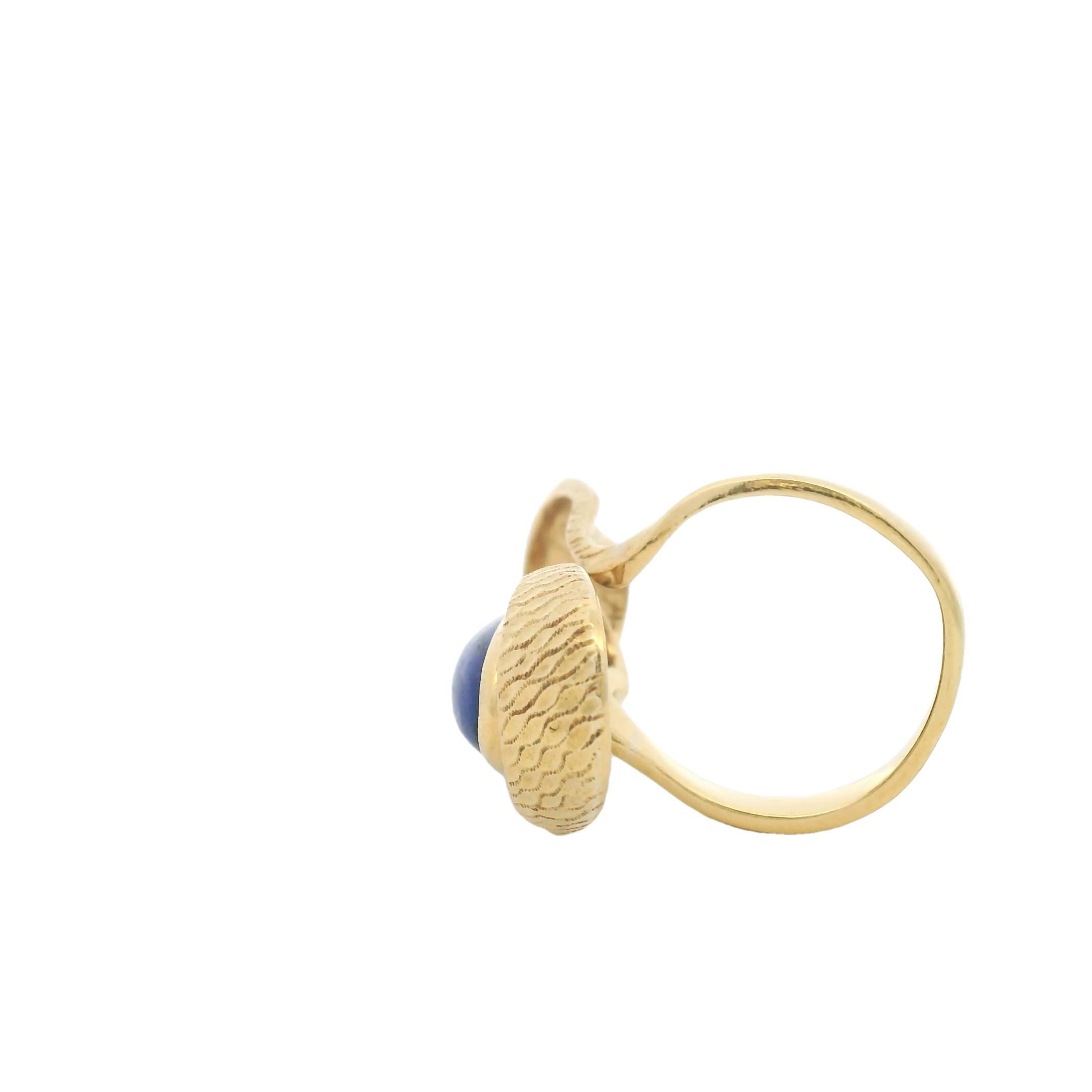 Exemple frappant du design moderniste américain des années 1970, cette bague sculpturale présente un riche cabochon ovale de lapis-lazuli de 1,75 carat serti dans une forme fluide et asymétrique en or jaune 14 carats. La surface texturée de l'or