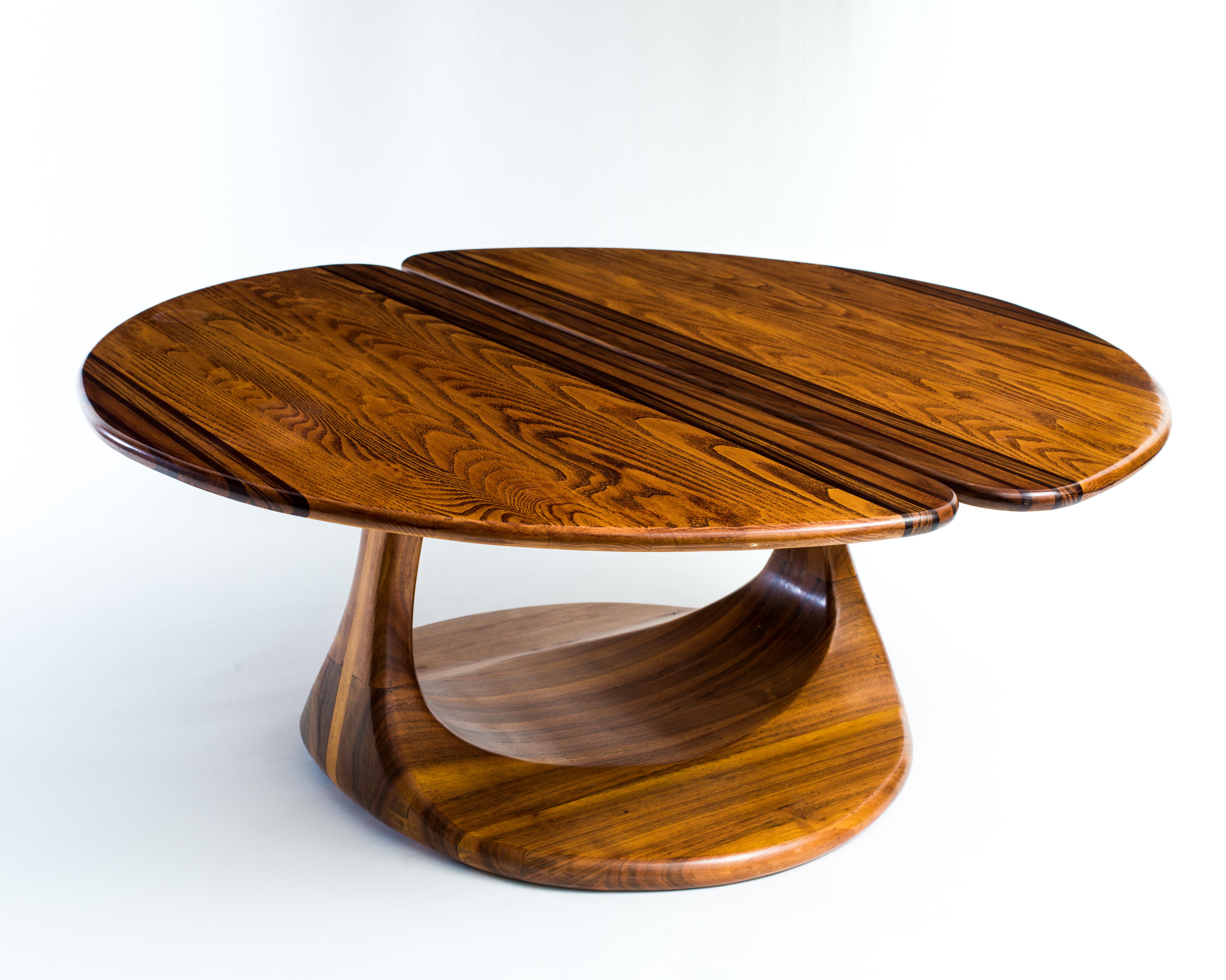 A handmade craft movement table with joined demilune tops in stained oak with dramatically expressive grain, supported by a sculptural, stack laminated base in (we believe) walnut. The artist deliberately left the top surfaces sanded just shy of