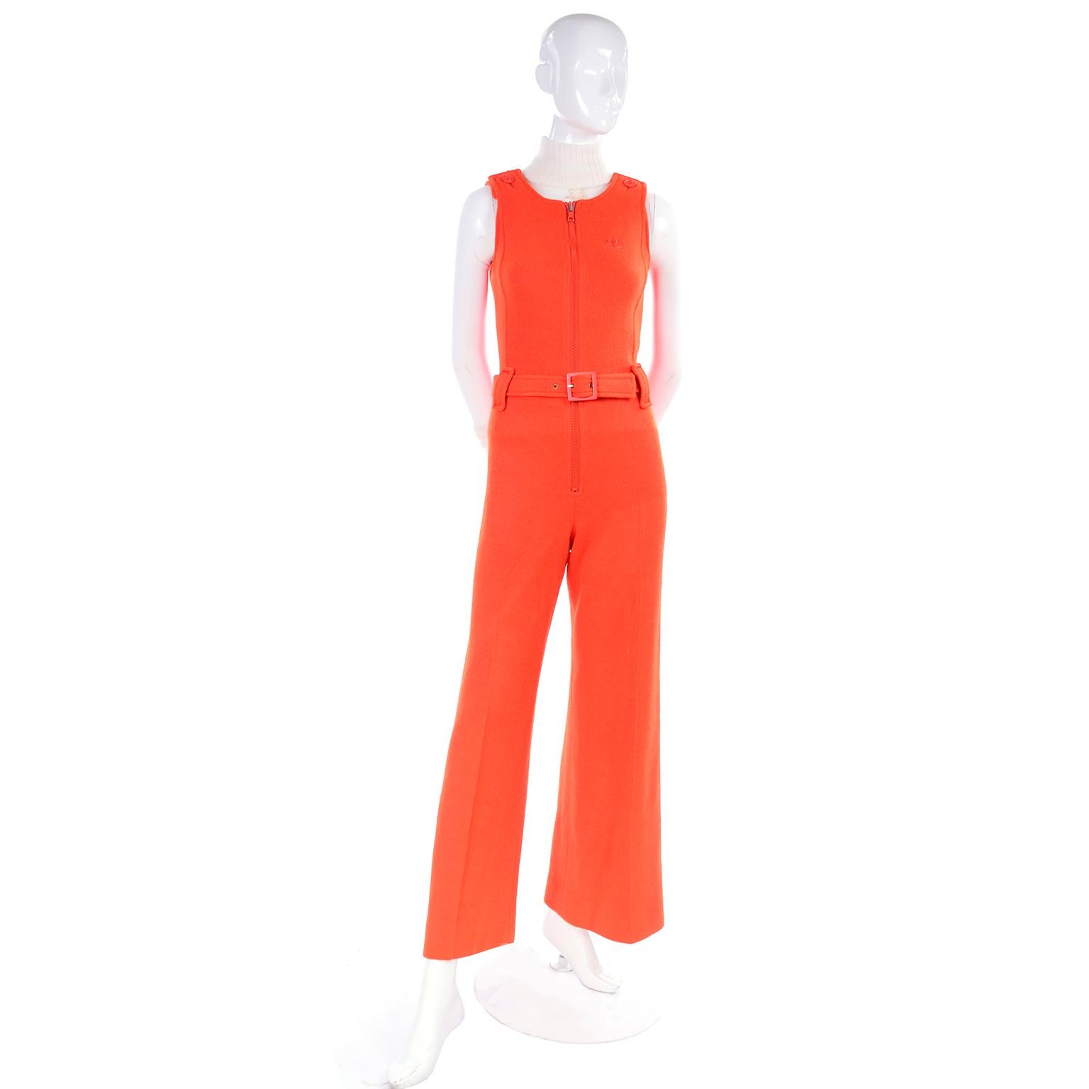 This is an amazing, rare vintage early 1970's orange jumpsuit and sheer white top ensemble from Andre Courrèges. The zip front orange knit jumpsuit has its original belt and the Courreges signature logo on the front. The sheer mock turtleneck top