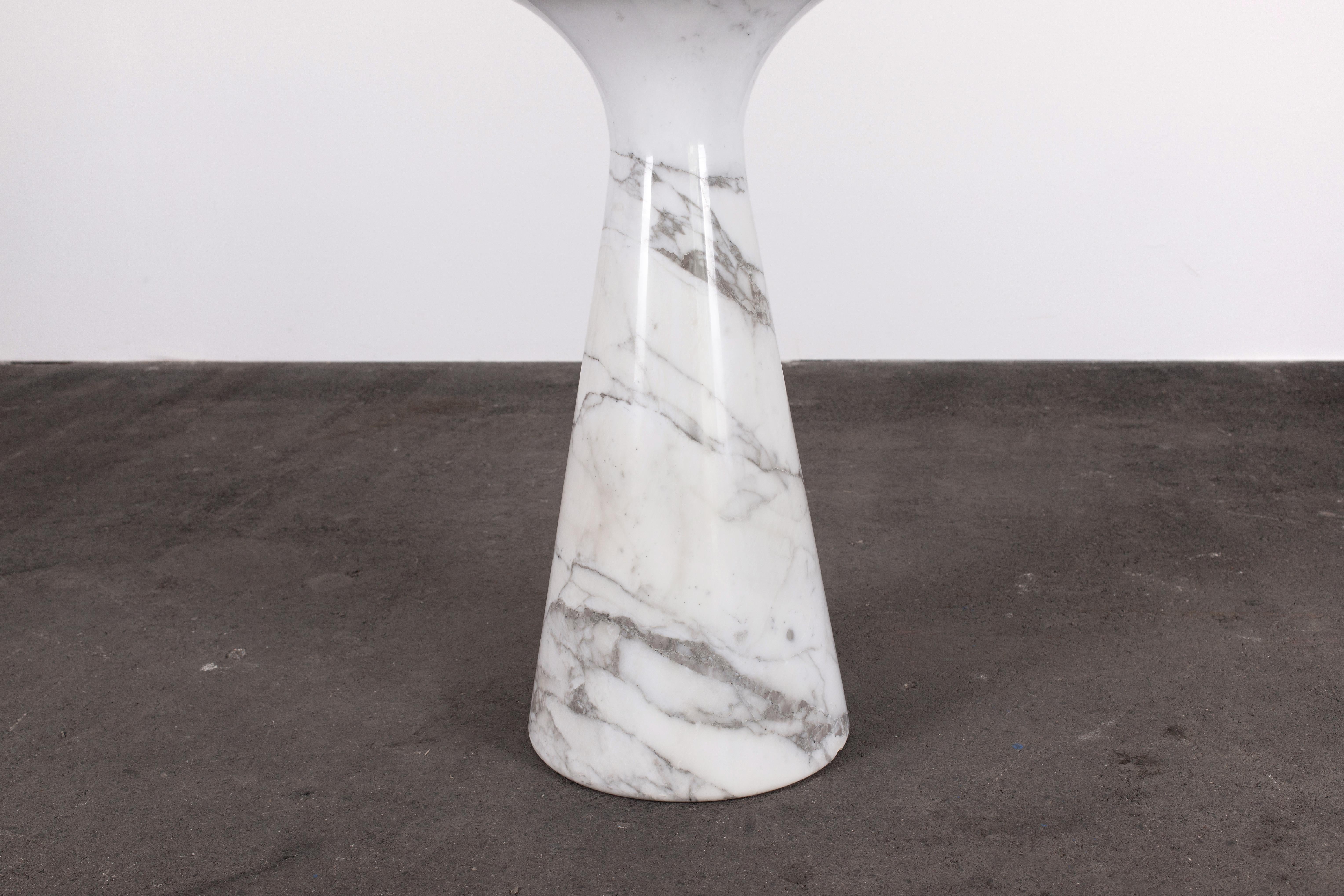 Mesa de comedor de pedestal redondo Angelo Mangiarotti para Skipper, Organic Modern de los años 70, de mármol blanco de Carrara muy trabajado, con vetas azul grisáceo y sutiles motas metálicas. Esta mesa es de la M1 y mide 130 cm de diámetro.

El