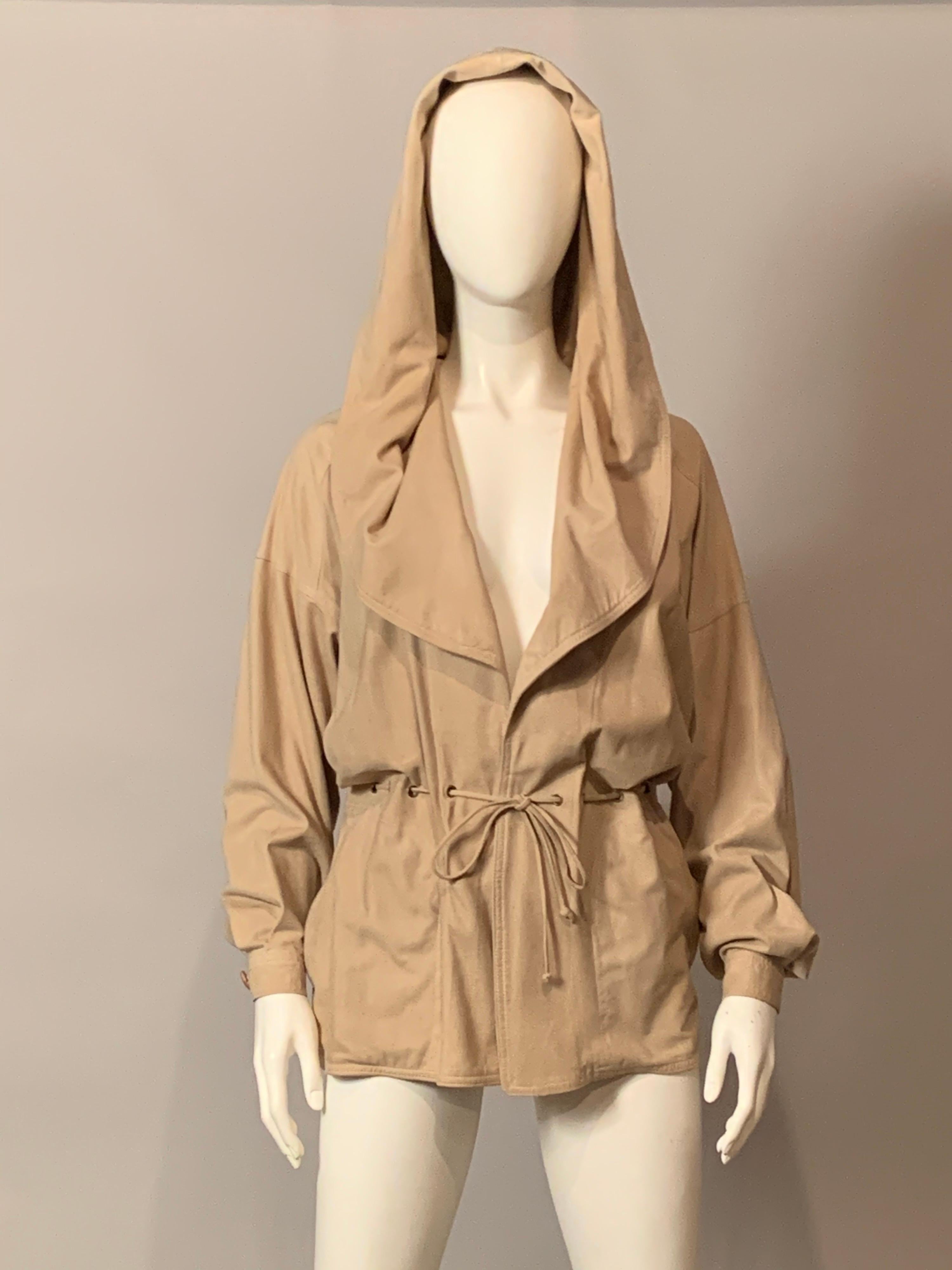 Pale beige butter soft chamois suede, unlined and with only a drawstring waist cinch for closure, and a generous hood or collar is emblematic of 1970's hippie chic.  The unlined jacket has dropped shoulders, two large pockets and wooden buttons on