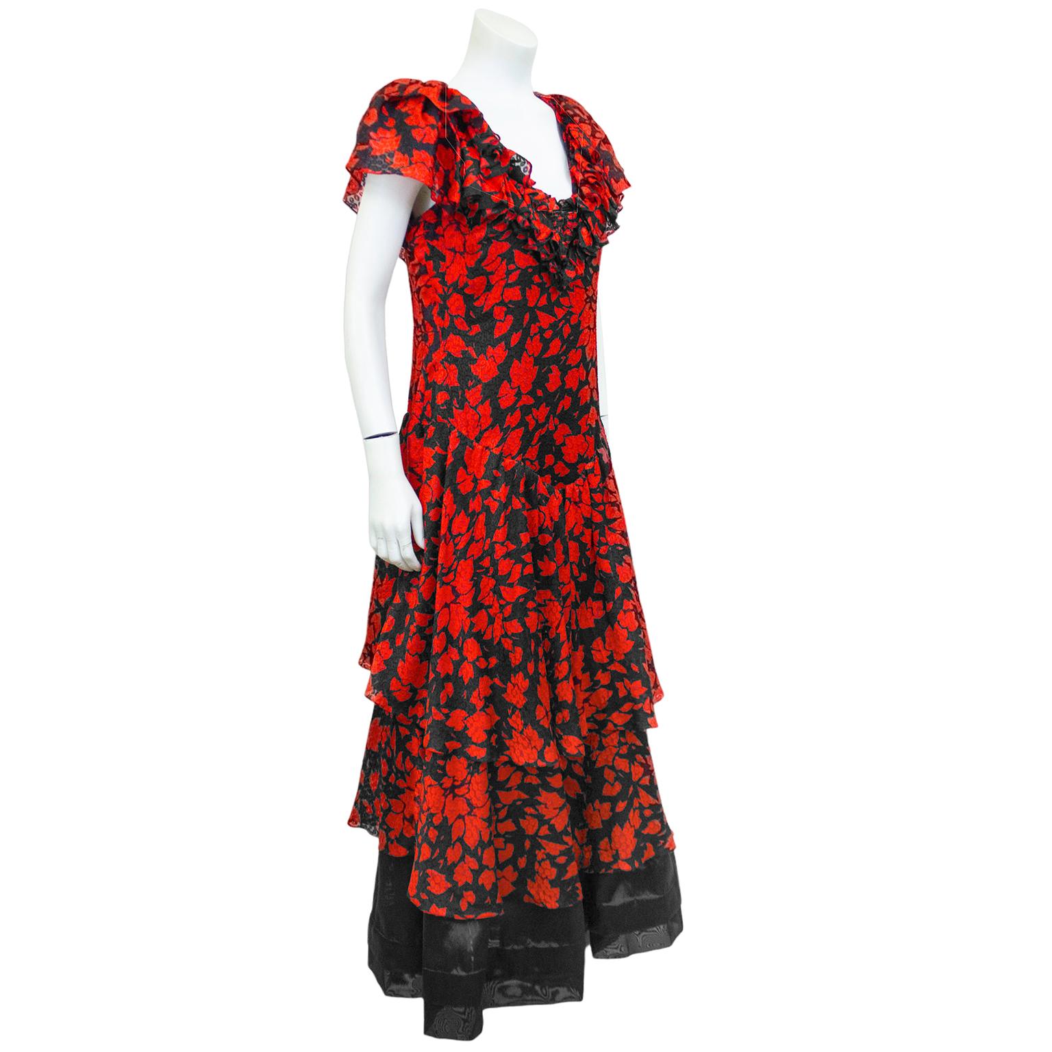 Romantisches Kleid aus Seidenjacquard mit rotem und schwarzem Blattdruck aus den 1970er Jahren. Mit Rüsche an der Brust, kurzen, romantischen Ärmeln, Bindeband im Nacken, leicht fallender Taille und gestuftem Rock. Schwarzer Unterrock zeigt sich am