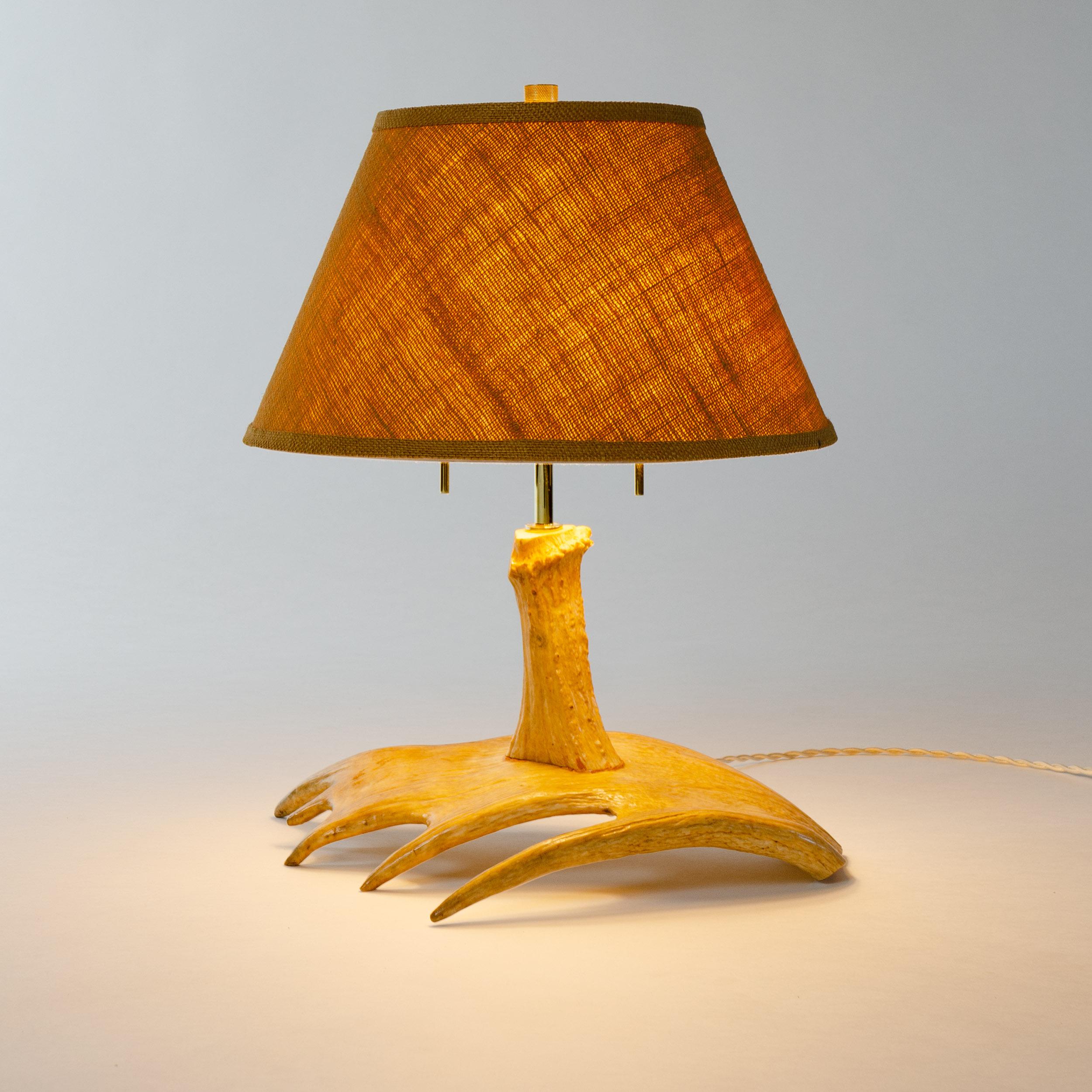 Unique, finely crafted, last quarter of the 20th century lighting device modeled from a moose antler, specifically the five point palm of the antler forms the wide base sitting beneath a thick, single antler tine mounted vertically to support the