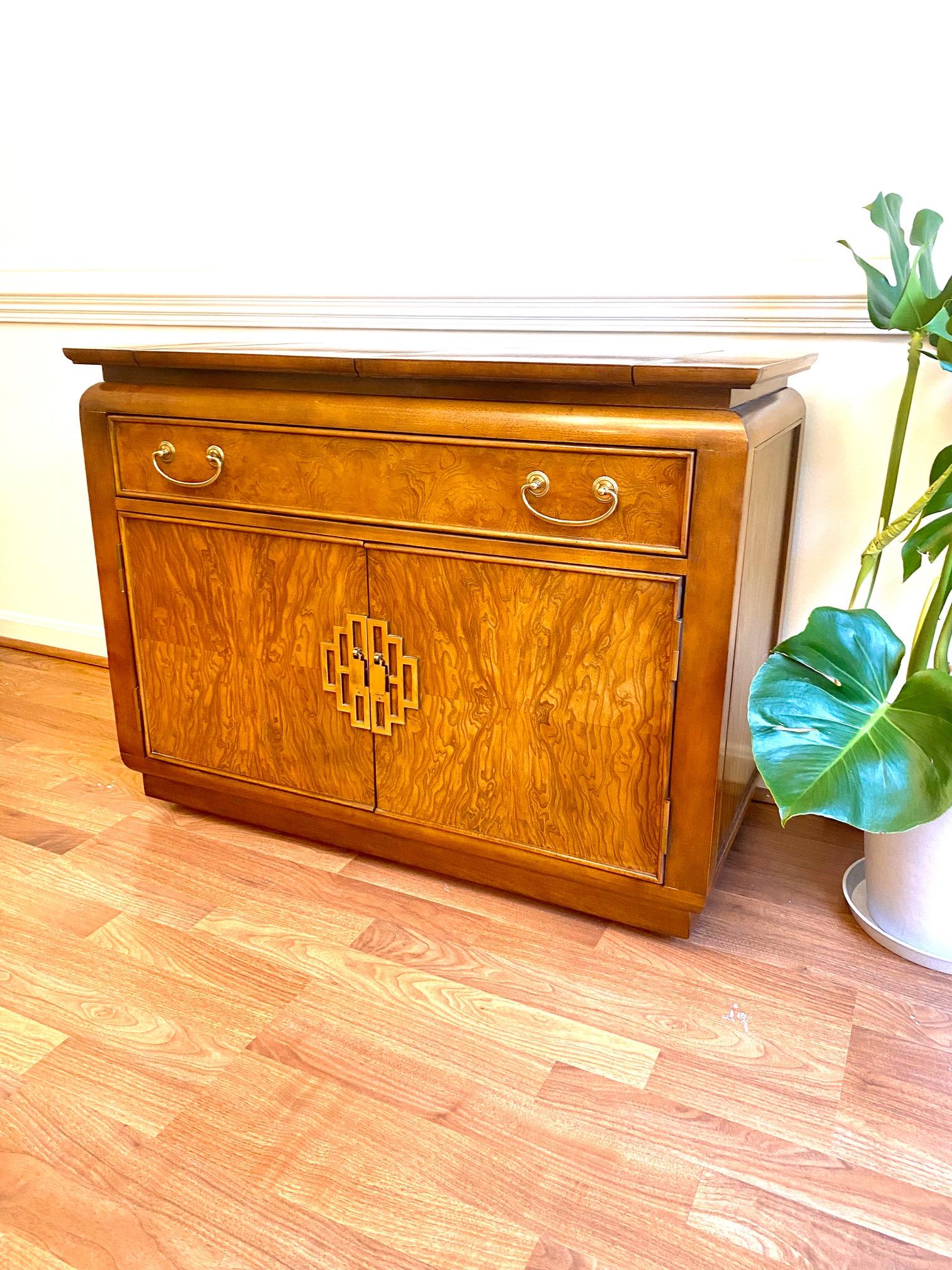 A stunning Art Deco style maple burlwood dry bar cabinet designed by Raymond Sabota for Century Furniture as a part of the Chin Hua collection circa 1970s. The burl front shines against the chinoiserie style brass hardware and pulls, and the top