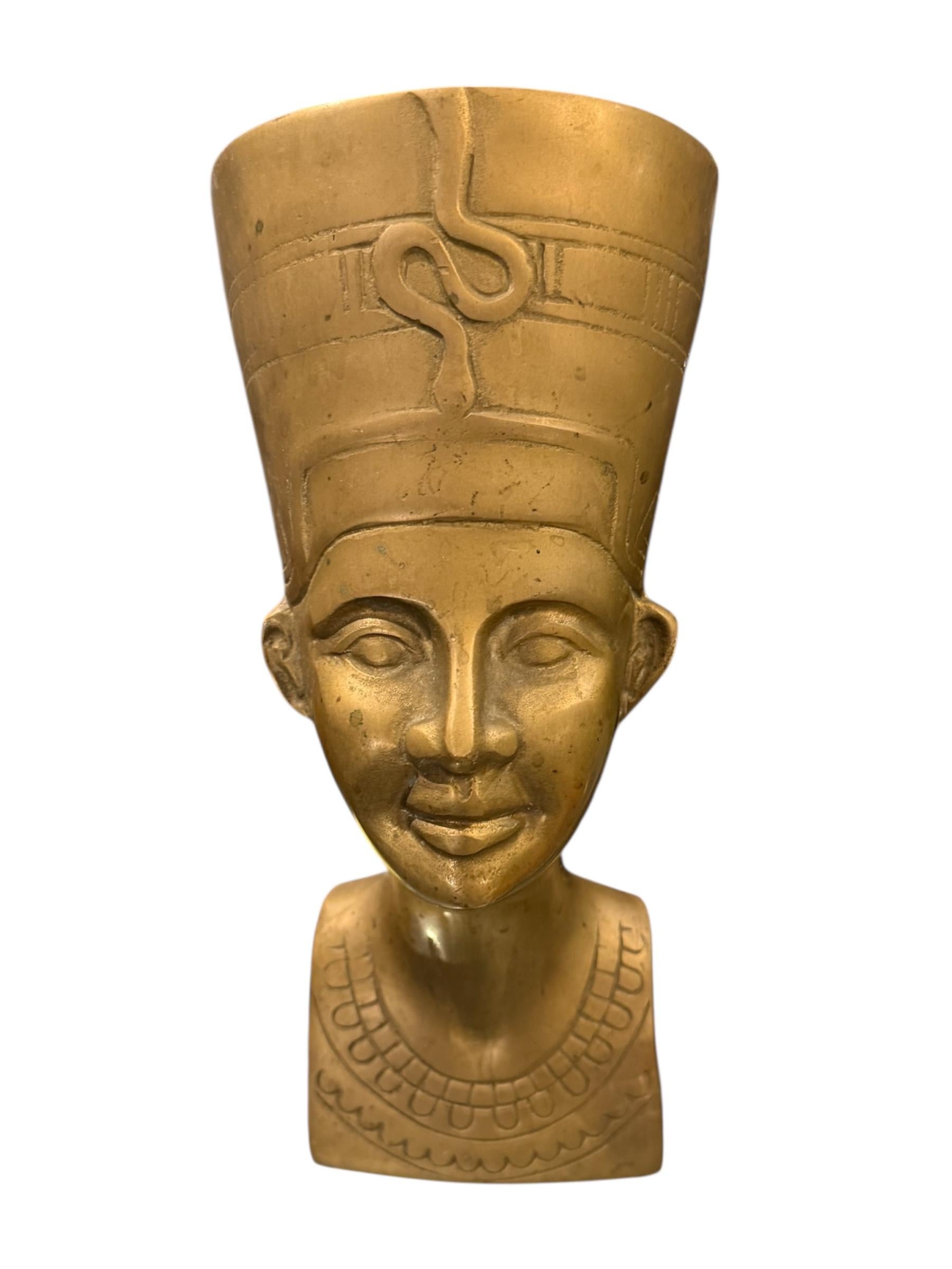 Immergiti nel glamour dorato del passato con questa straordinaria scultura Art Deco Egyptian Revival degli anni Settanta. Realizzato in ottone massiccio, questo elegante busto raffigura la regina Nefertiti, una delle figure più iconiche dell'antico