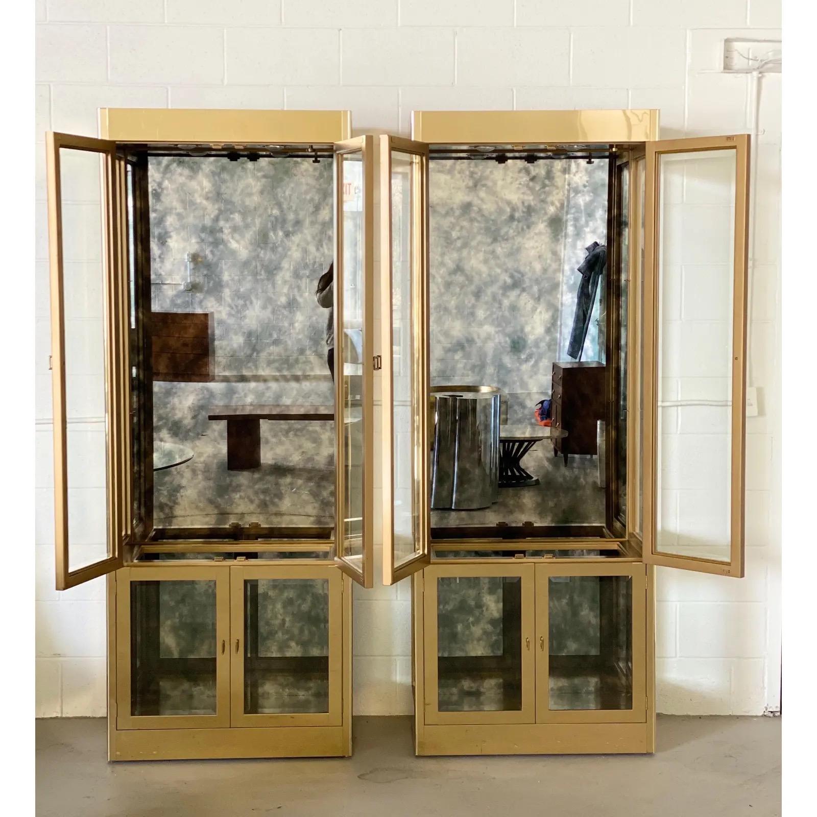 We are very pleased to offer an extraordinary, sophisticated, set of display cases by Mastercraft, circa the 1970s. These highly desirable pieces feature lacquered brass, beveled glass on all doors and side panels and an antique finish mirror