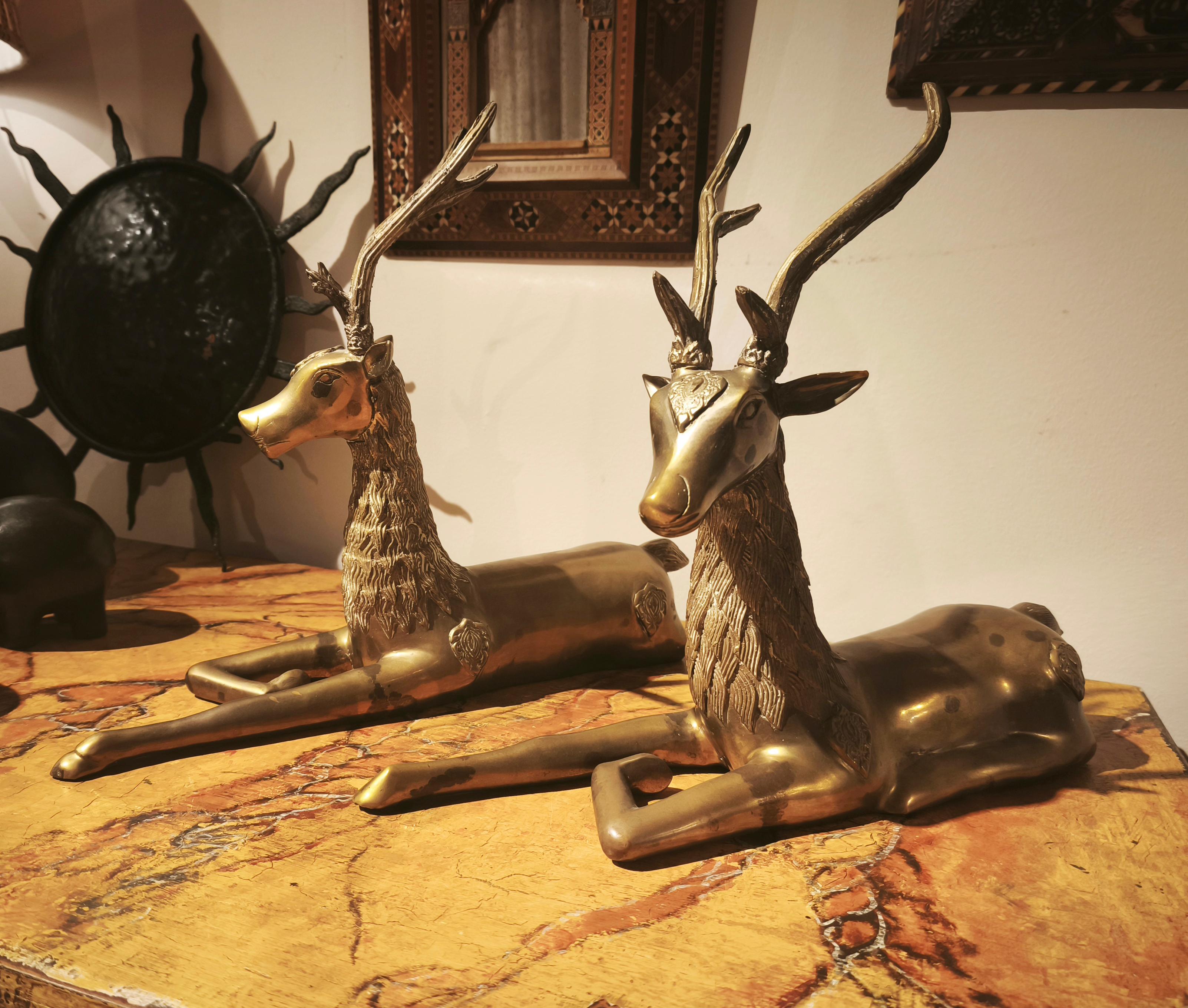 Un'elegante coppia di cervi reclinabili realizzati in bronzo massiccio con una raffinata finitura dorata. Ispirate al design asiatico, le figure si distinguono per la modellazione dettagliata delle corna e della pelliccia, che conferiscono