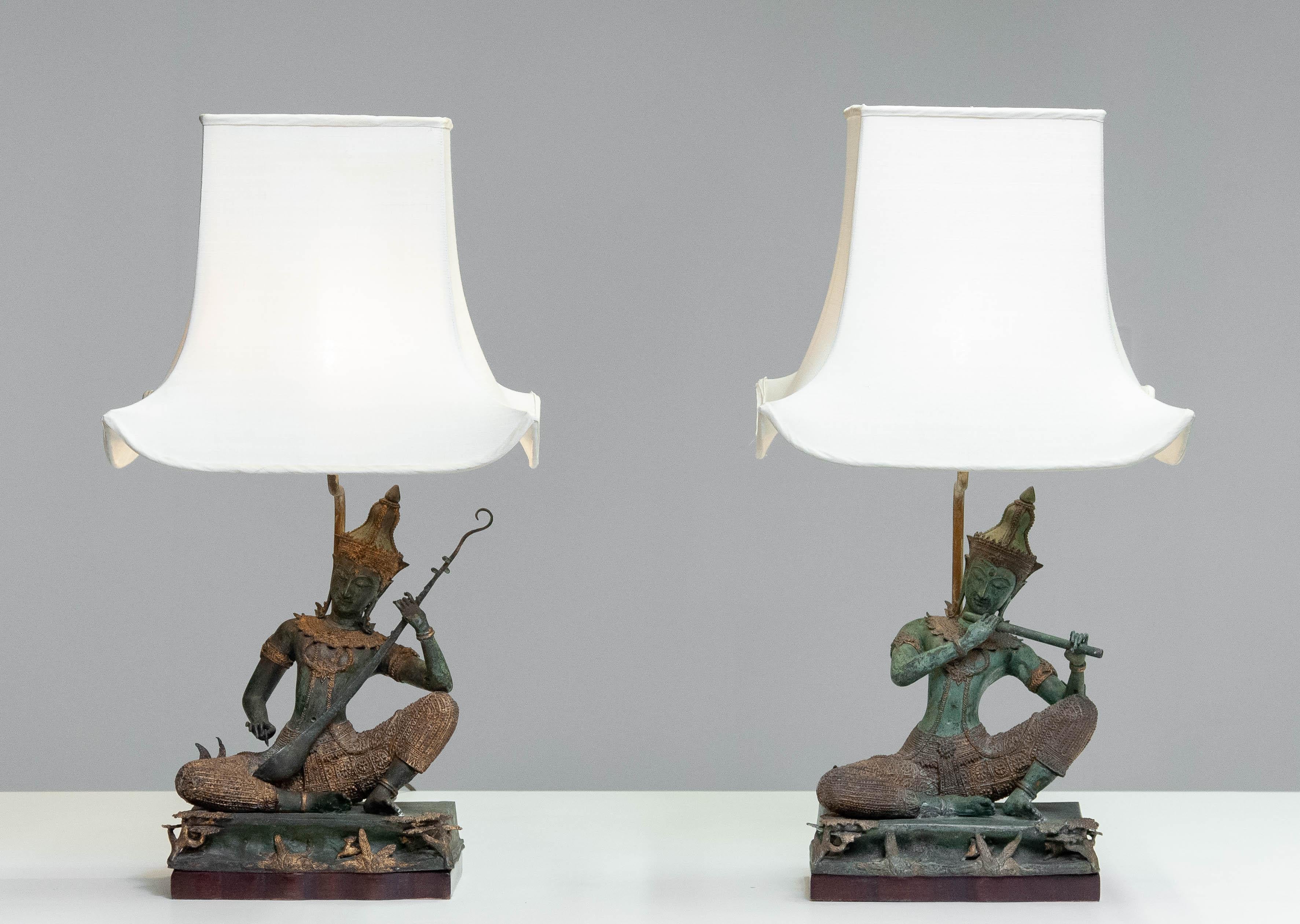 Pair beautiful and very decorative tables lamps from Thailand with extremely detailed brass statues from Phra Aphai Mani from the 1970s. One playing a Khlui flute and the other playing the Jakhee ( three stringed guitar ).

Both sitting and