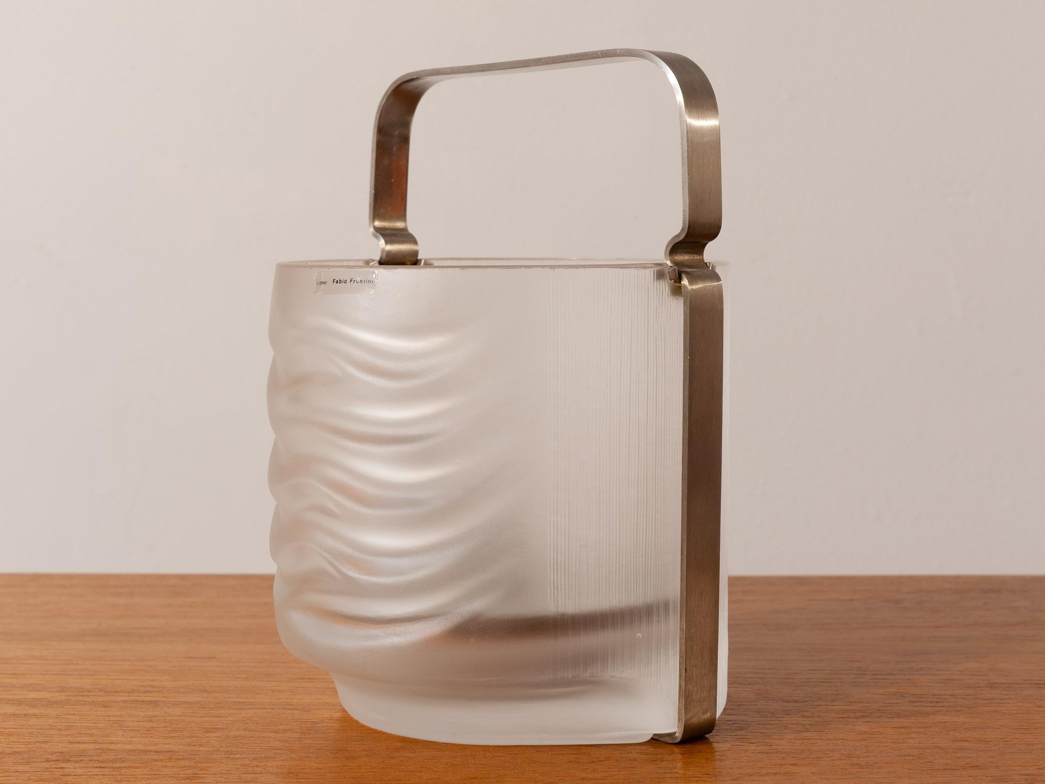 1970s Italian Azteca ice bucket designed by Fabio Frontini for Arnolfo di Cambio. The item is made from frosted crystal glass with a stainless steel feature handle. A stainless steel drainage plate sits in the bottom to allow the melted water to sit