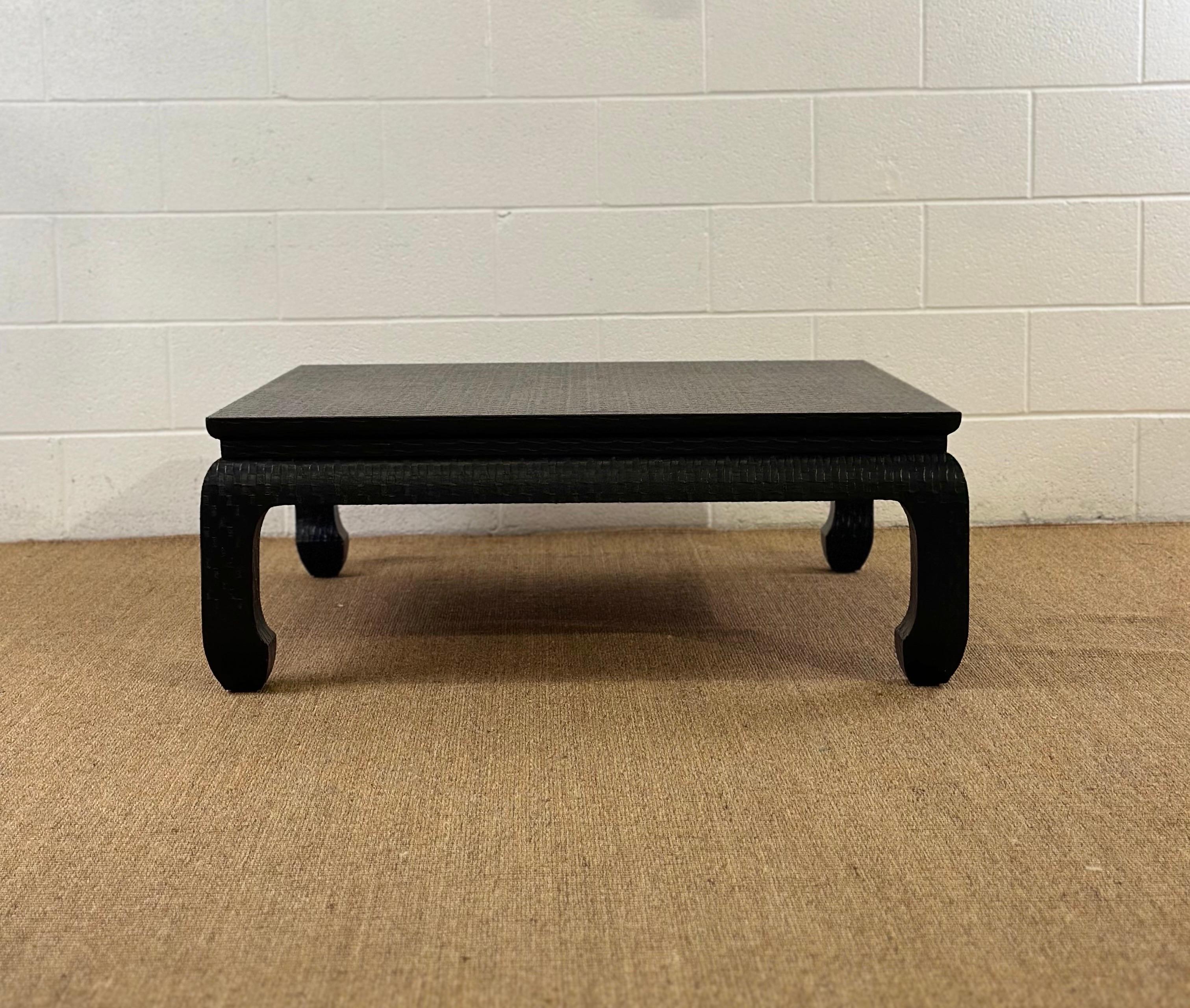 We are very pleased to offer a chic coffee table, by Baker Furniture, circa the 1970s. This exquisite table showcases a textured, patterned raffia wrap in an elegant black finish, echoing the renowned style of Karl Springer.  This piece combines
