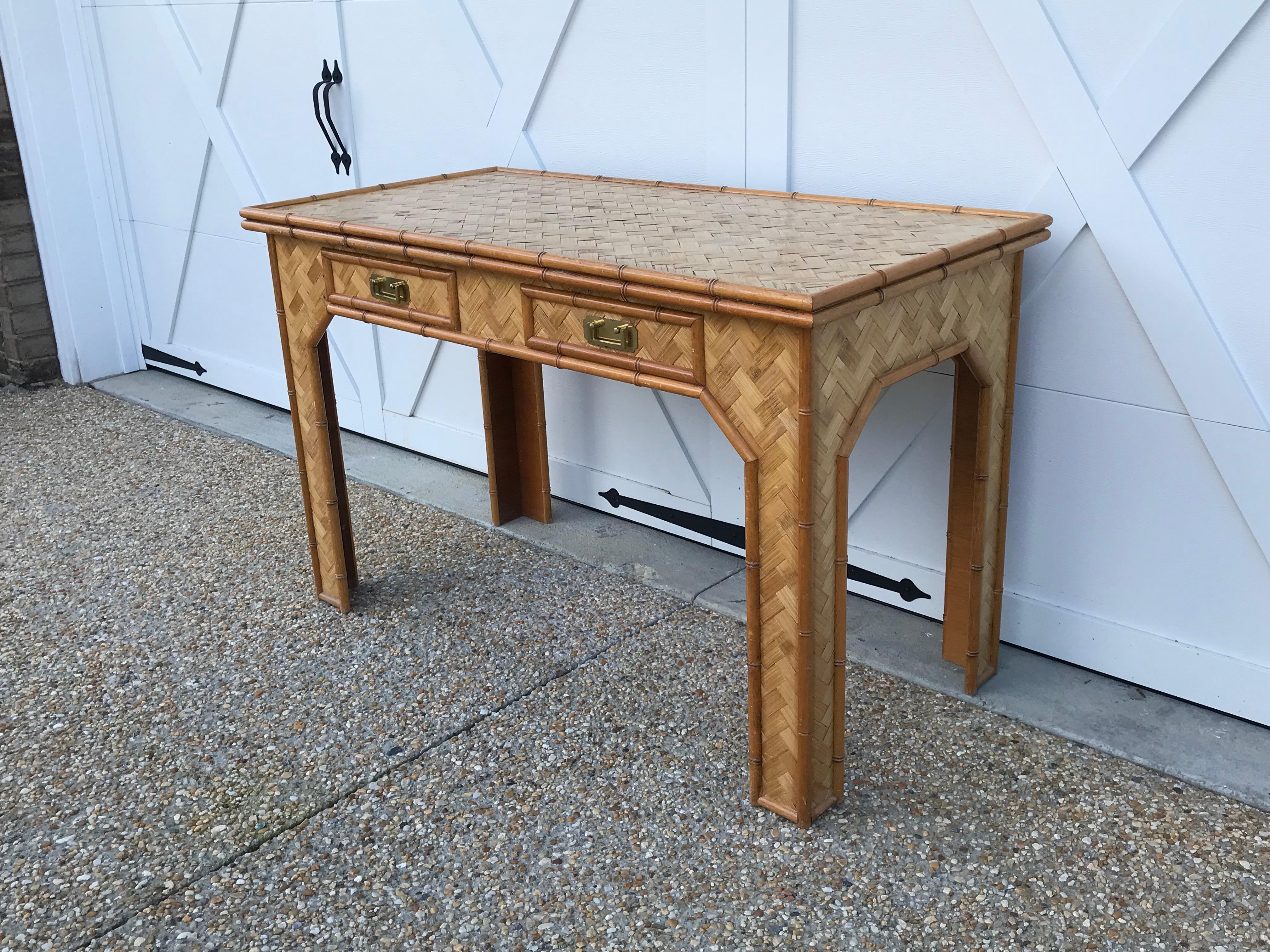 Offered is a stunning, 1970s bamboo writing desk with brass campaign-style hardware. This desk is in great condition and has ample room for working. The two drawers add a sleek storage component. Sturdy and stable, not wobbly. Top has a small lip,
