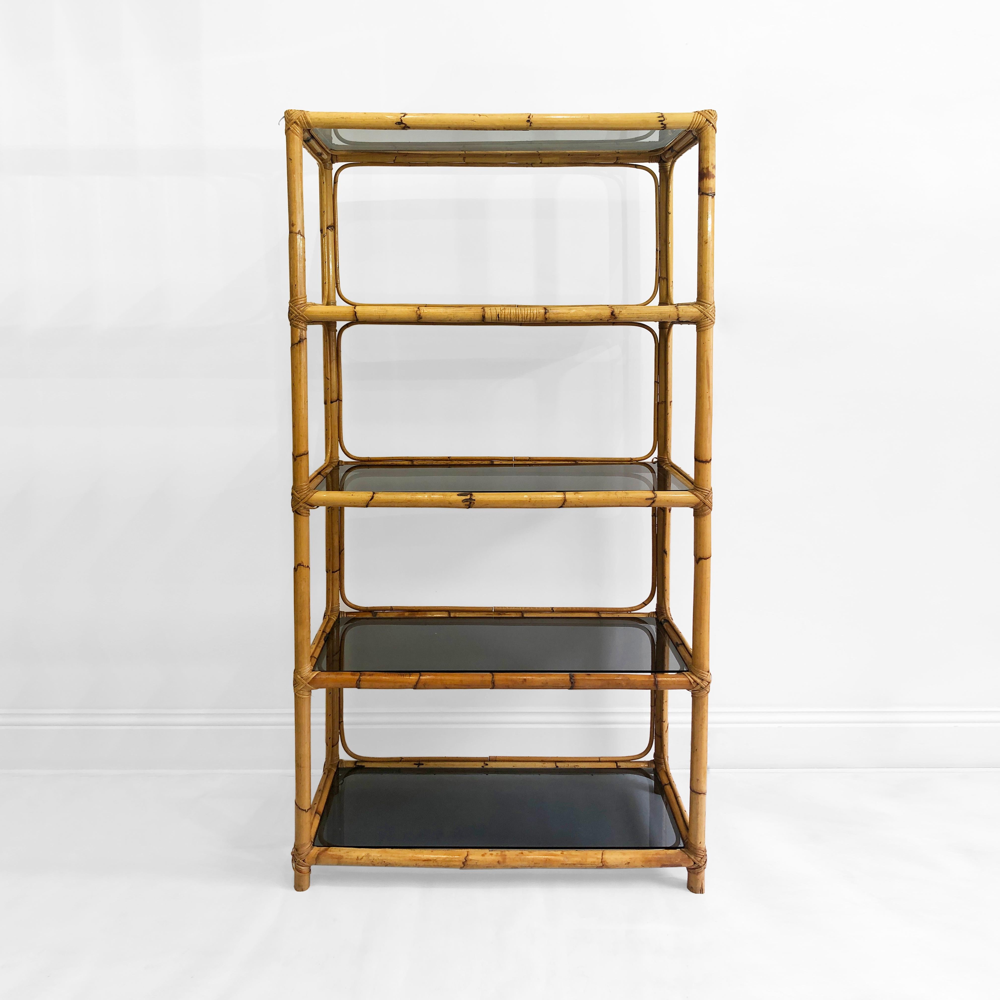 Vintage bamboo and smoked glass shelving etagere originated from Italy in the 1970s.

The etagere houses five smoked glass shelves which are surrounded by a thick bamboo frame. the joints of the frame are wrapped with rattan or bamboo extract
