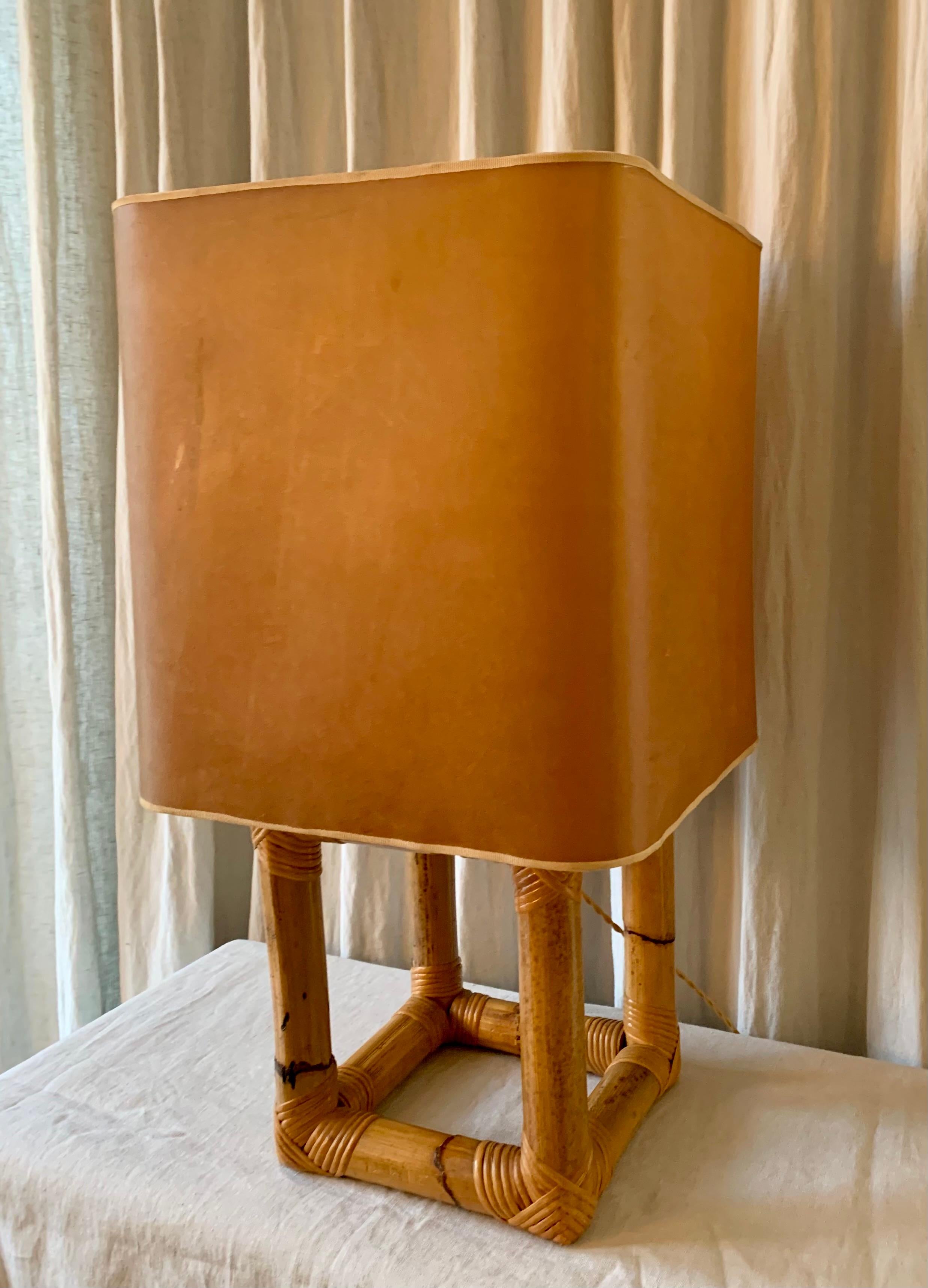 Elegante lampe de table vintage en bambou des années 1970 avec le grand abat-jour d'origine en fine peau d'animal qui permet à la lumière de transparaître de manière chaleureuse et subtile.  
