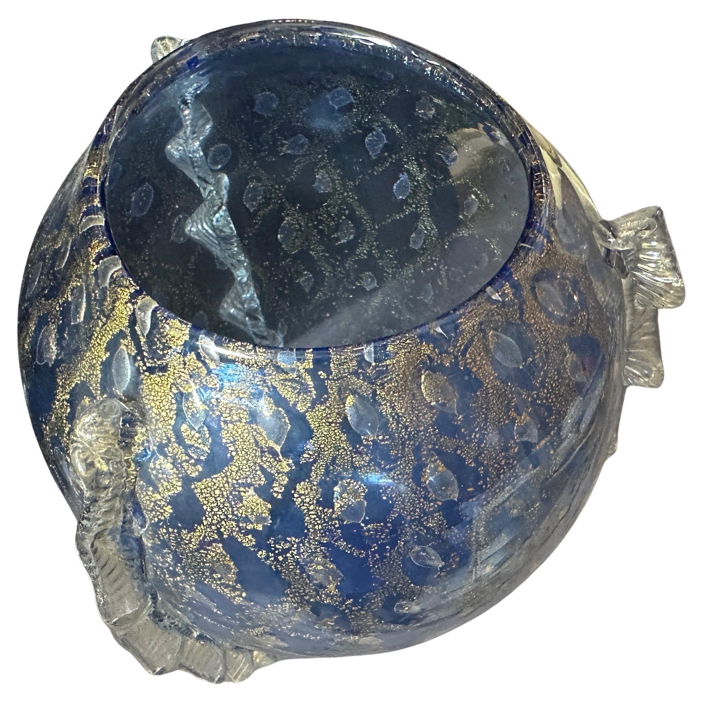 This 1970s beautiful Murano glass vase in a Barovier-style exhibits the distinct characteristics of Murano glass craftsmanship, renowned for its elaborate and luxurious designs.
The vase is primarily a deep blue, adorned with intricate gold leaf