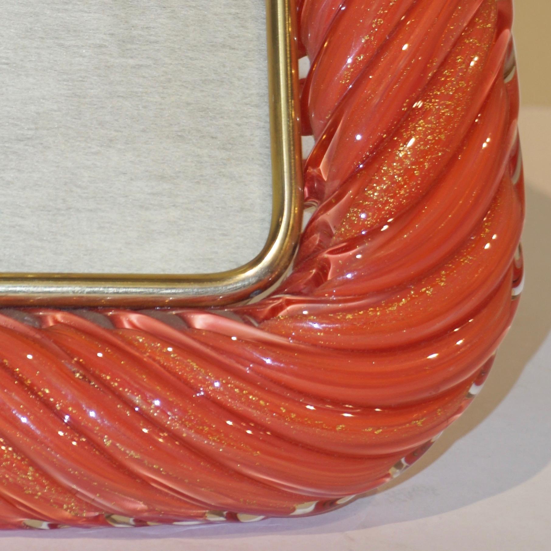 Sophisticated and elegant vintage picture frame in thick blown Murano glass of unusual color in a reddish / pink shade of coral: the crystal clear glass frame worked with “torchon” technique, handcrafted twisted blown Murano glass that amplifies the