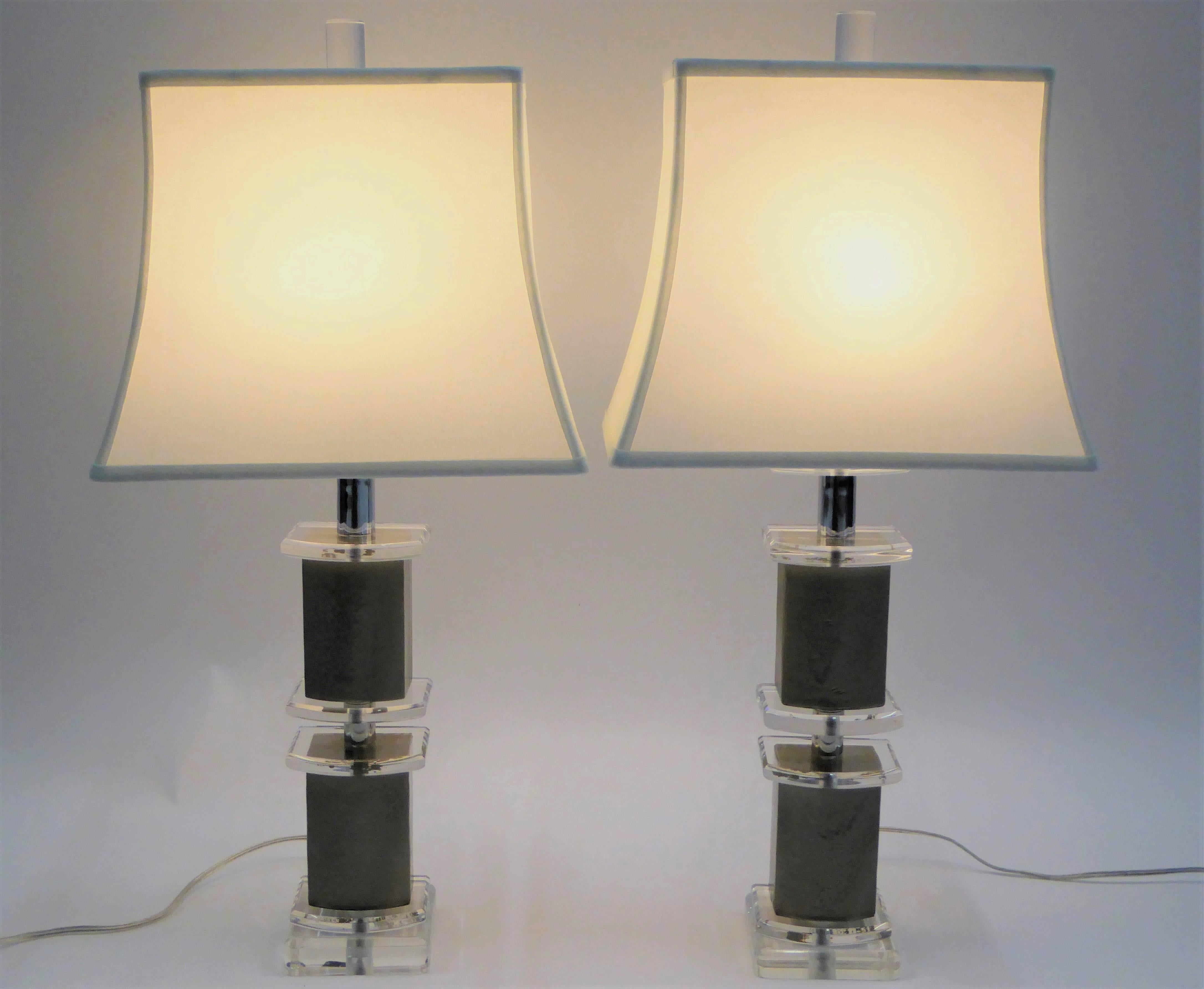 Swanky and urbane pair of 1970s Bauer Lucite and lacquered leather Lamps with a narrow profile of stepped levels of D-shaped Lucite and pewter colored lacquered leather covered blocks. All new wiring, new UL socket and Hi-Lo on cord switch. Custom