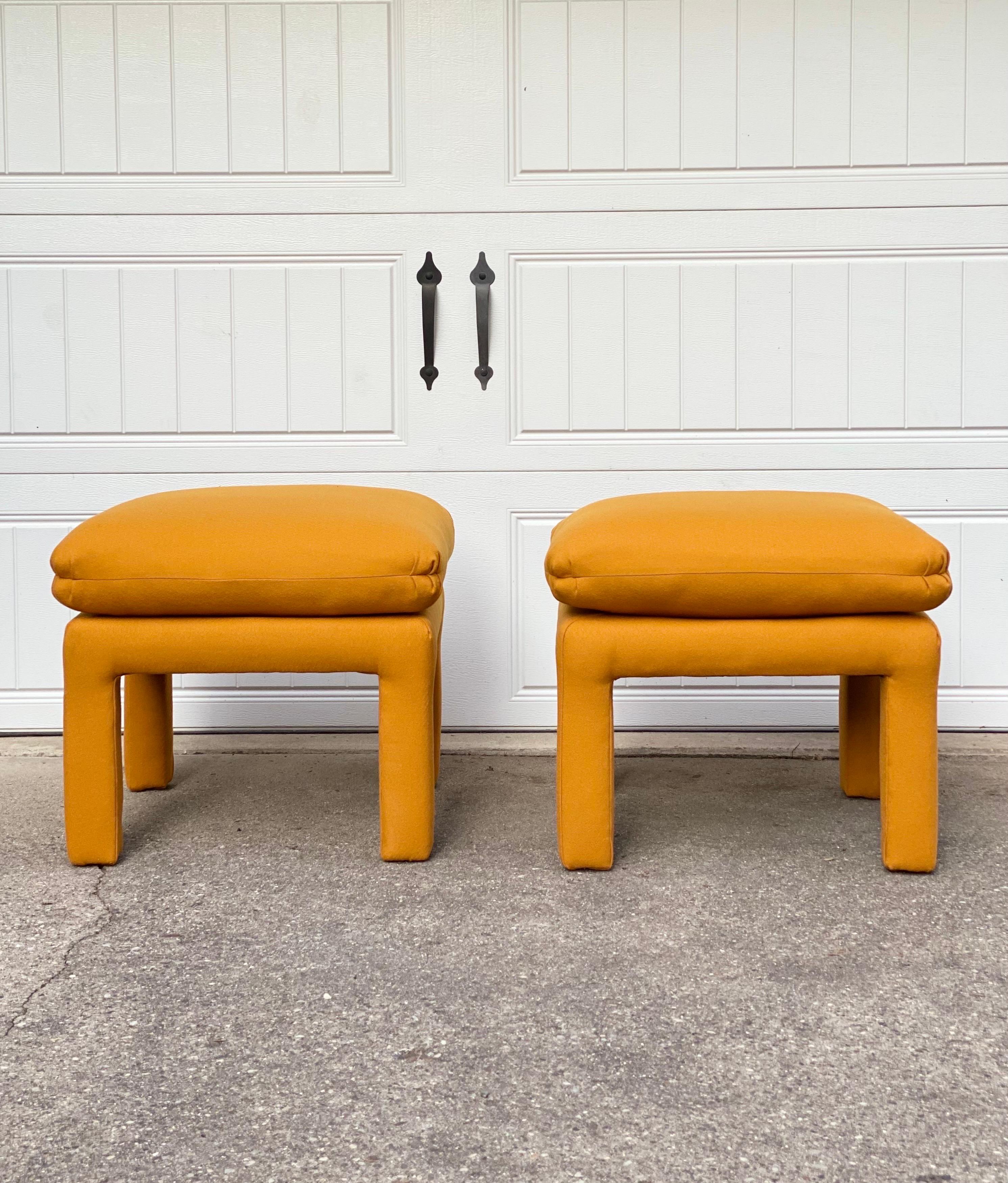 We are very pleased to offer a chic, vintage pair of Milo Baughman style ottomans, circa the 1970s. Elevate your living space with these captivating parson ottomans that have been beautifully reupholstered in a vibrant mustard-colored Maharam wool