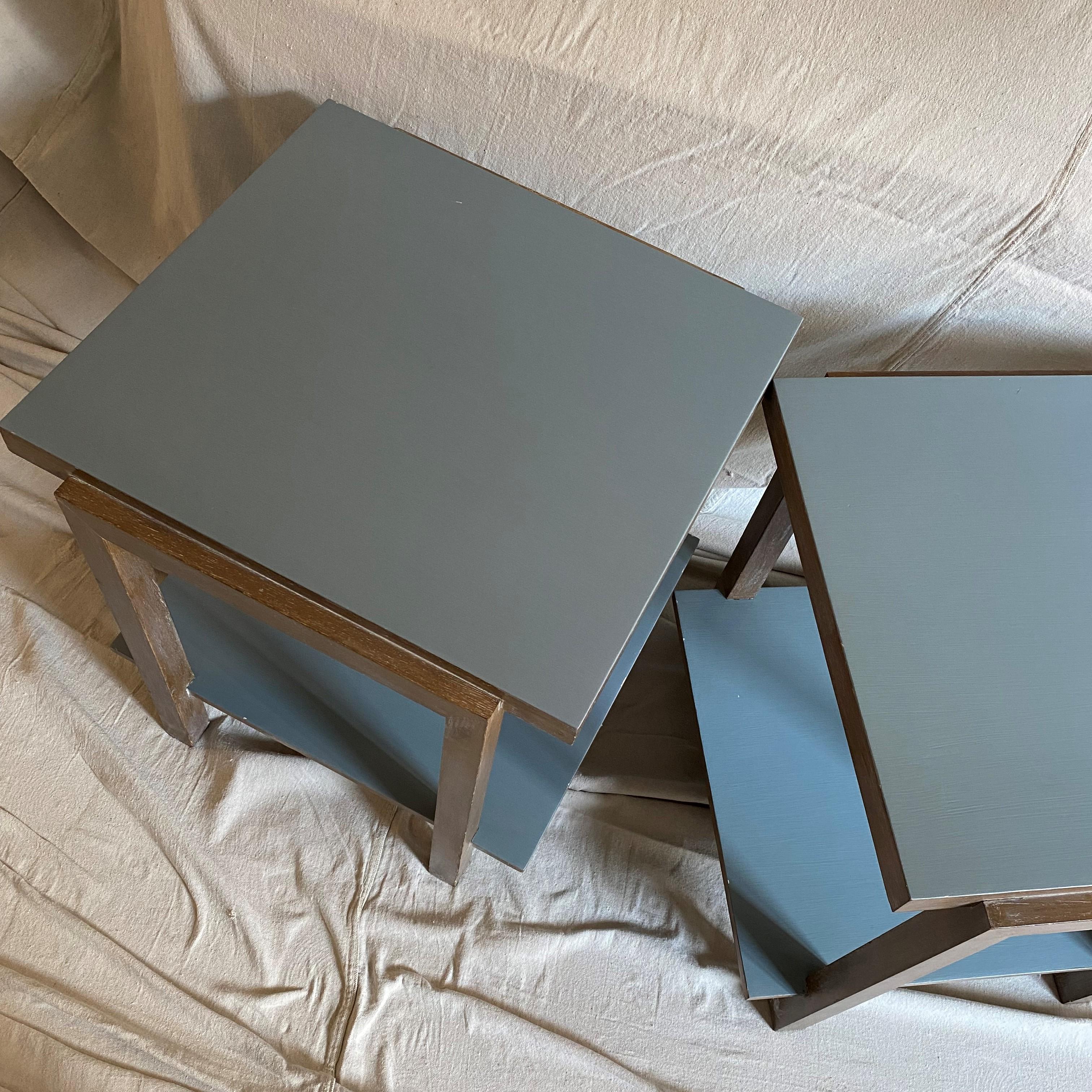 A pair of oak stained and painted occasional tables. The upper surface and lower shelf are in a painted finish easy to alter in a color of your choice if blue/gray is not ideal. The large proportions lend the tables to be placed side by side in