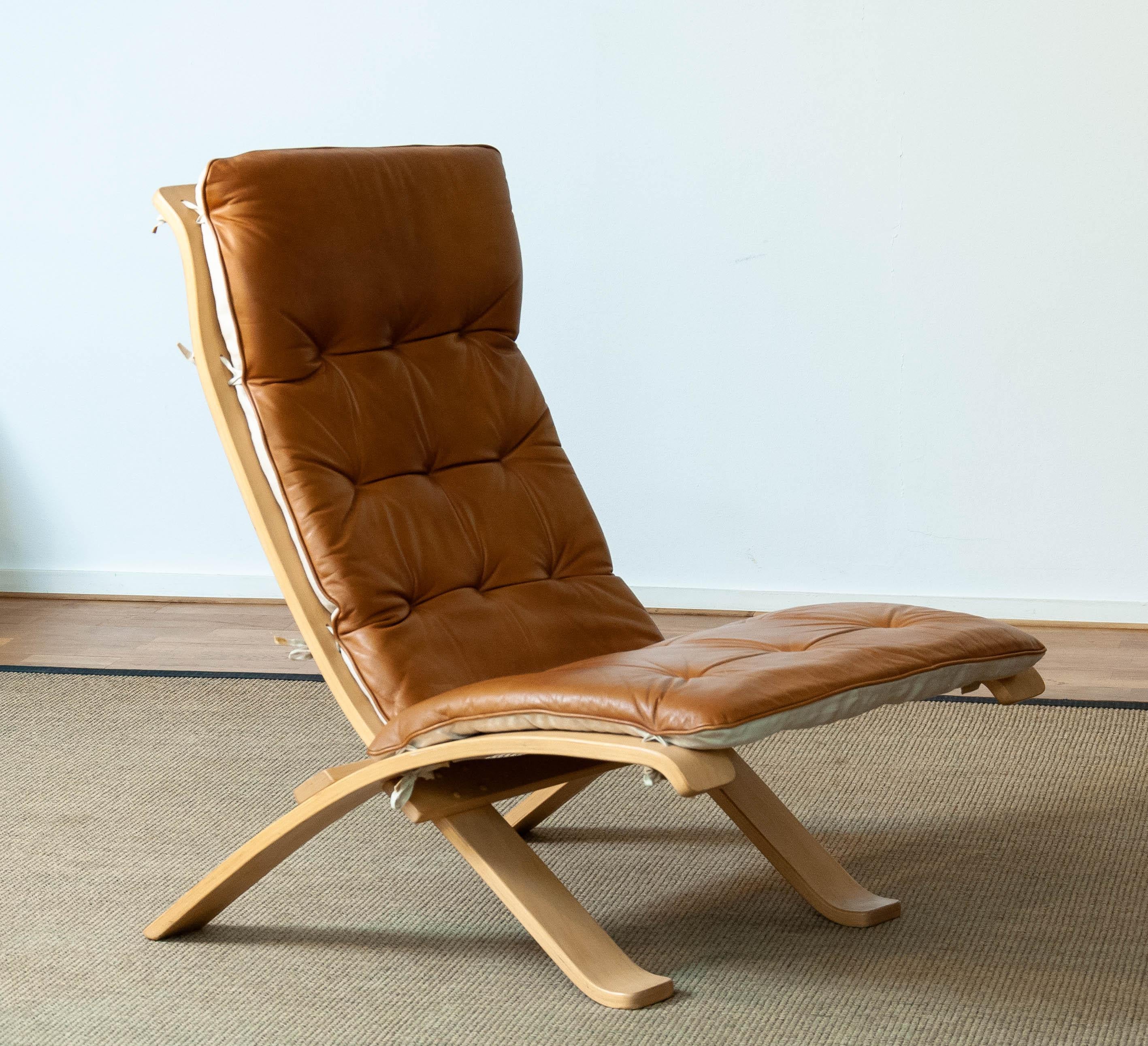 Chaise pliante extrêmement rare, conçue par Åke Foldes pour Nelo Sweden, en hêtre et recouverte de cuir cognac. Cette solution fantastique, qui consiste à n'installer un fauteuil extrêmement confortable dans votre salon qu'en cas de besoin, a été