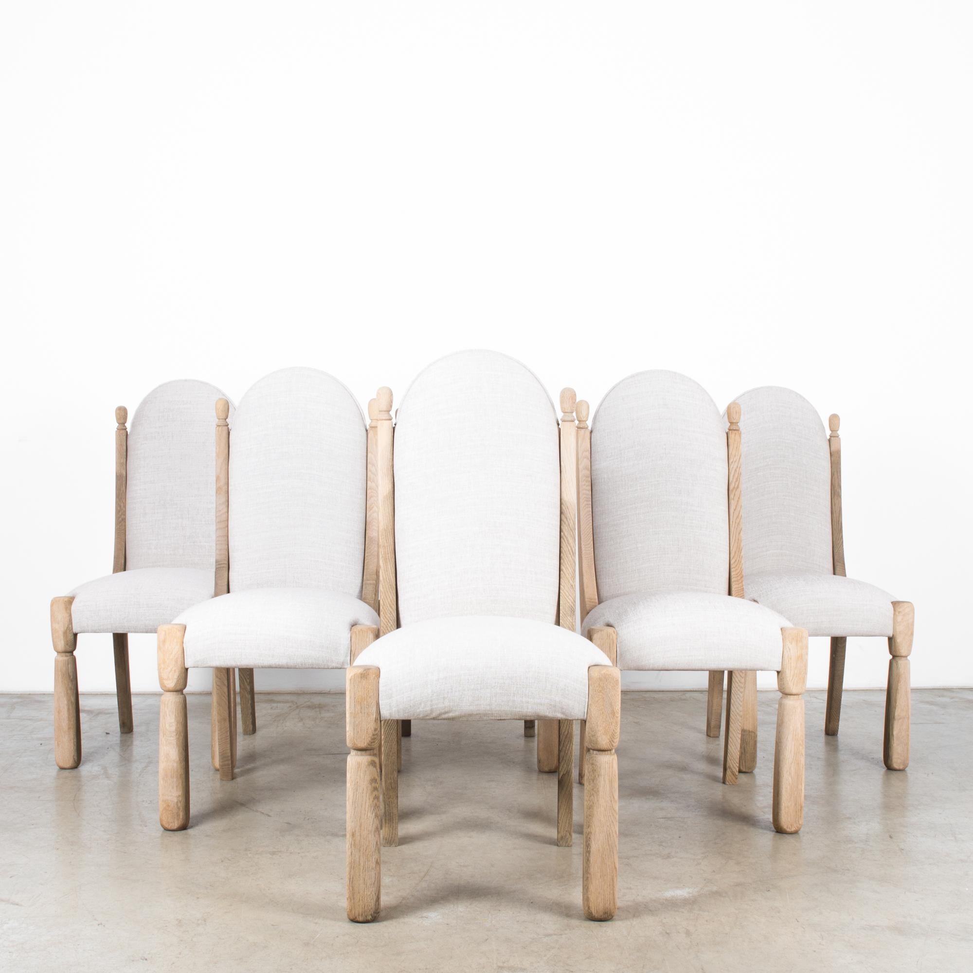 A set of six bleached oak dining chairs from Belgium, circa 1970. Like a company of manikins in their dress grays standing at attention. Angled back legs reaching up become frames for the soft grey arches of the seat backs. These are finely crafted