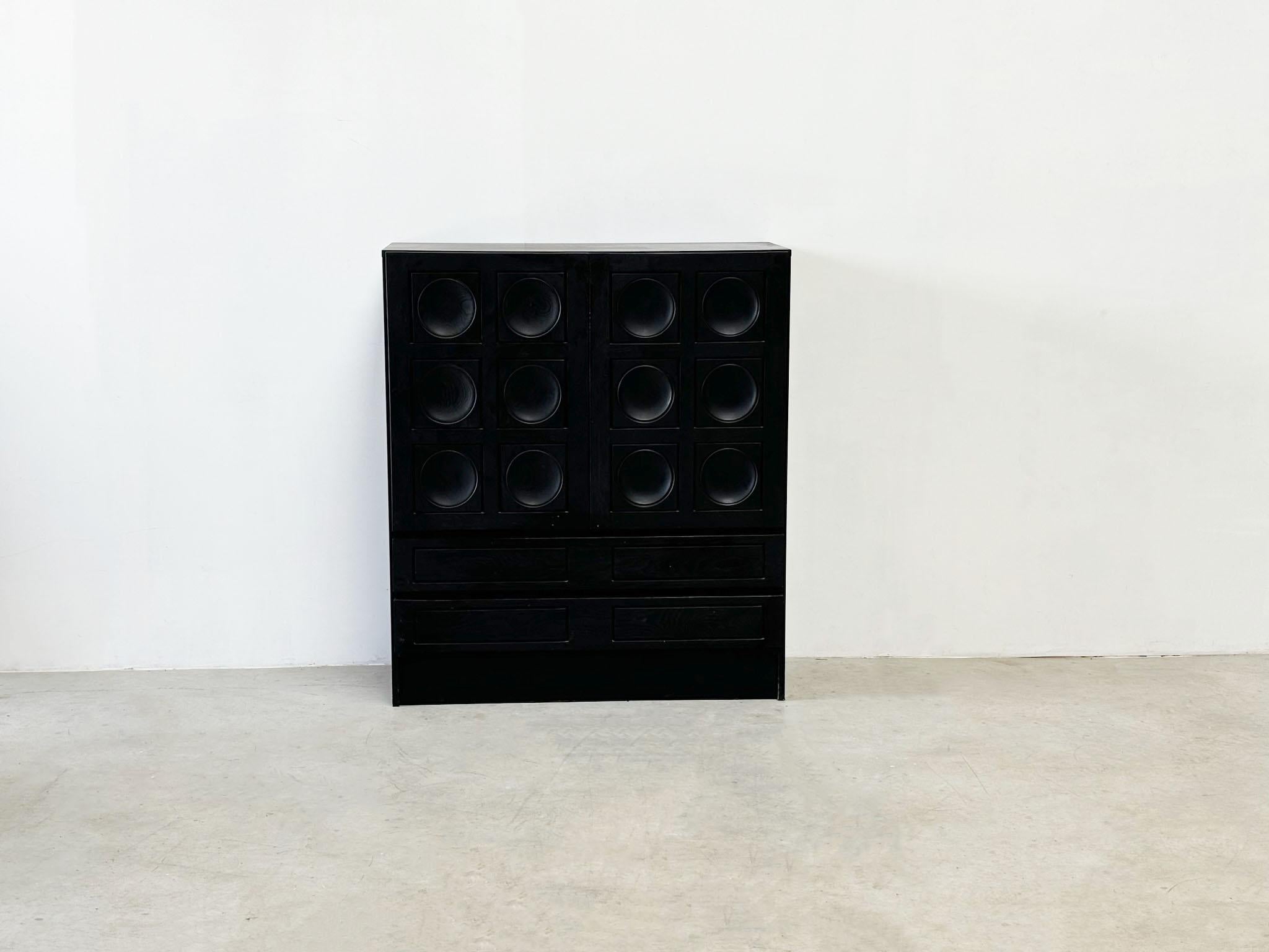 This 1970s black ebonized Belgian geometric door paneling bar by Musstering features a striking graphic pattern on the front doors. It serves as both a decorative piece and a functional storage or dry bar. It was made in the 1970's.

The cabinet is