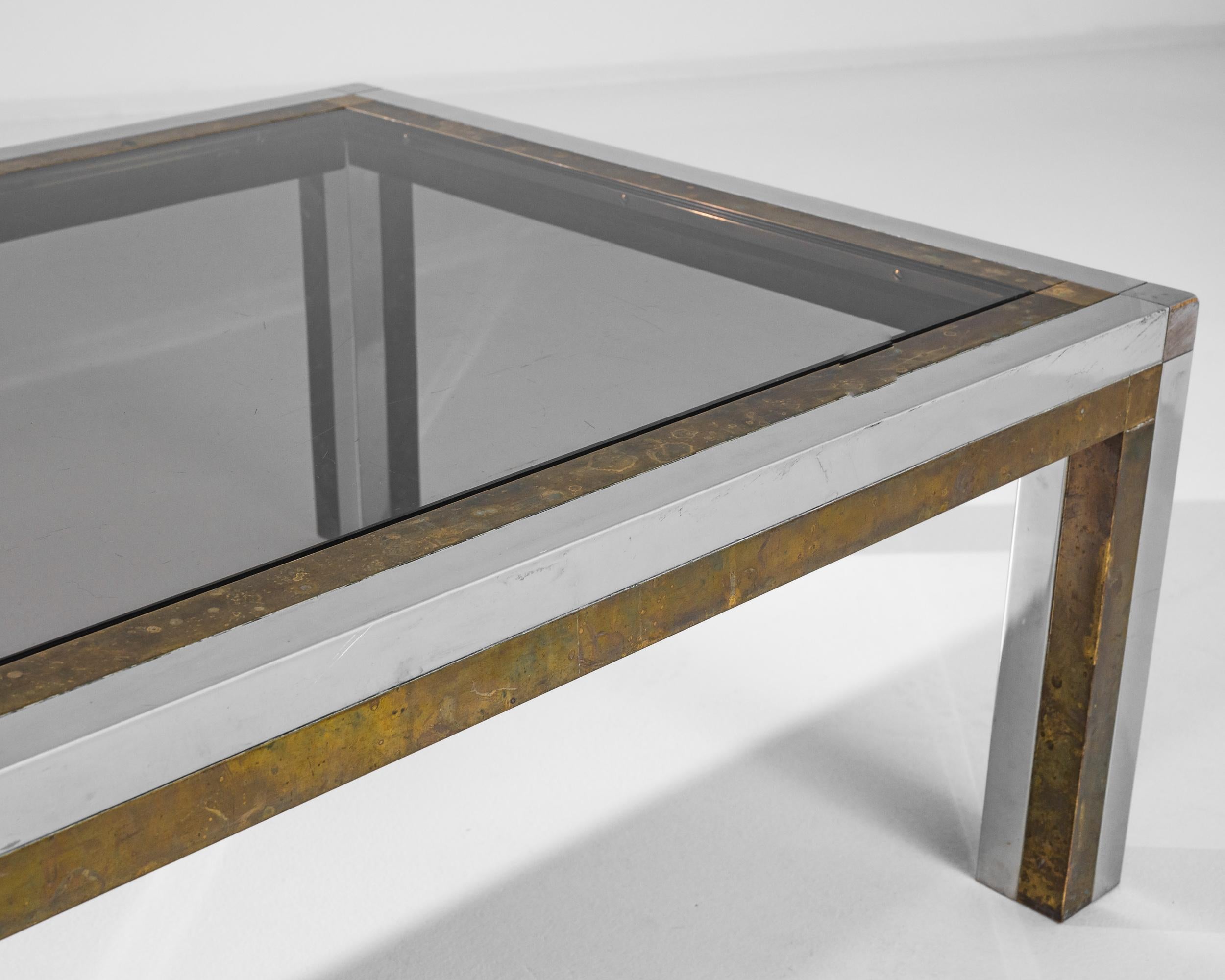 Indulge in the retro charm of this 1970s Belgian Metal Coffee Table. It is a perfect blend of sophistication and industrial flair. The table is made of a fusion of brass and chrome, giving it a unique and timeless aesthetic. The metal frame of the