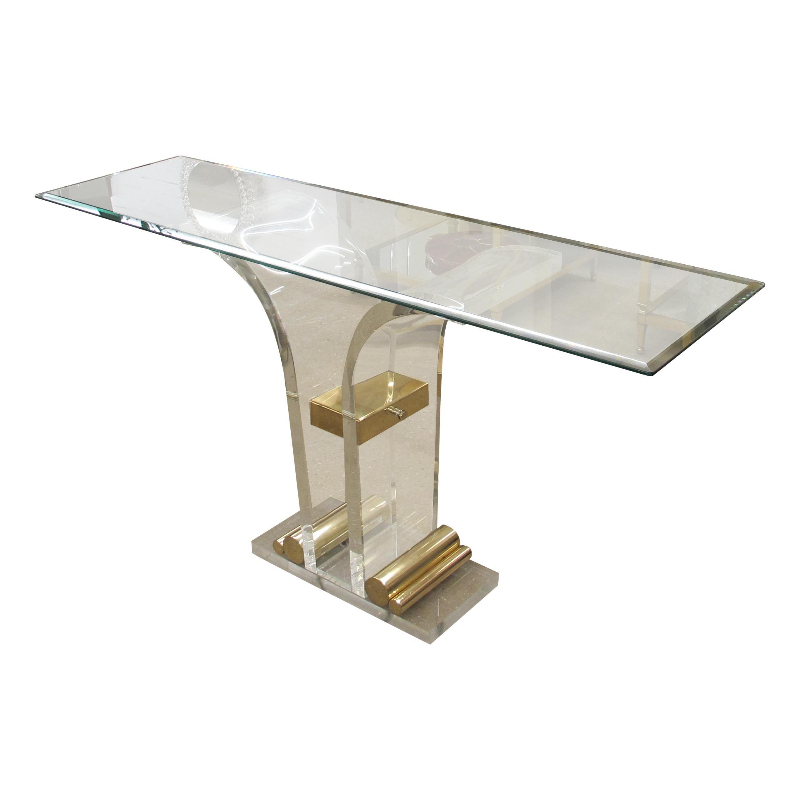 This elegant Belgian 1970s Perspex/Lucite console table boasts a sculptural design featuring a thick, original rectangular bevelled glass top. The piece is supported by a curved arched Lucite base with elegant brass detailing. The combination of