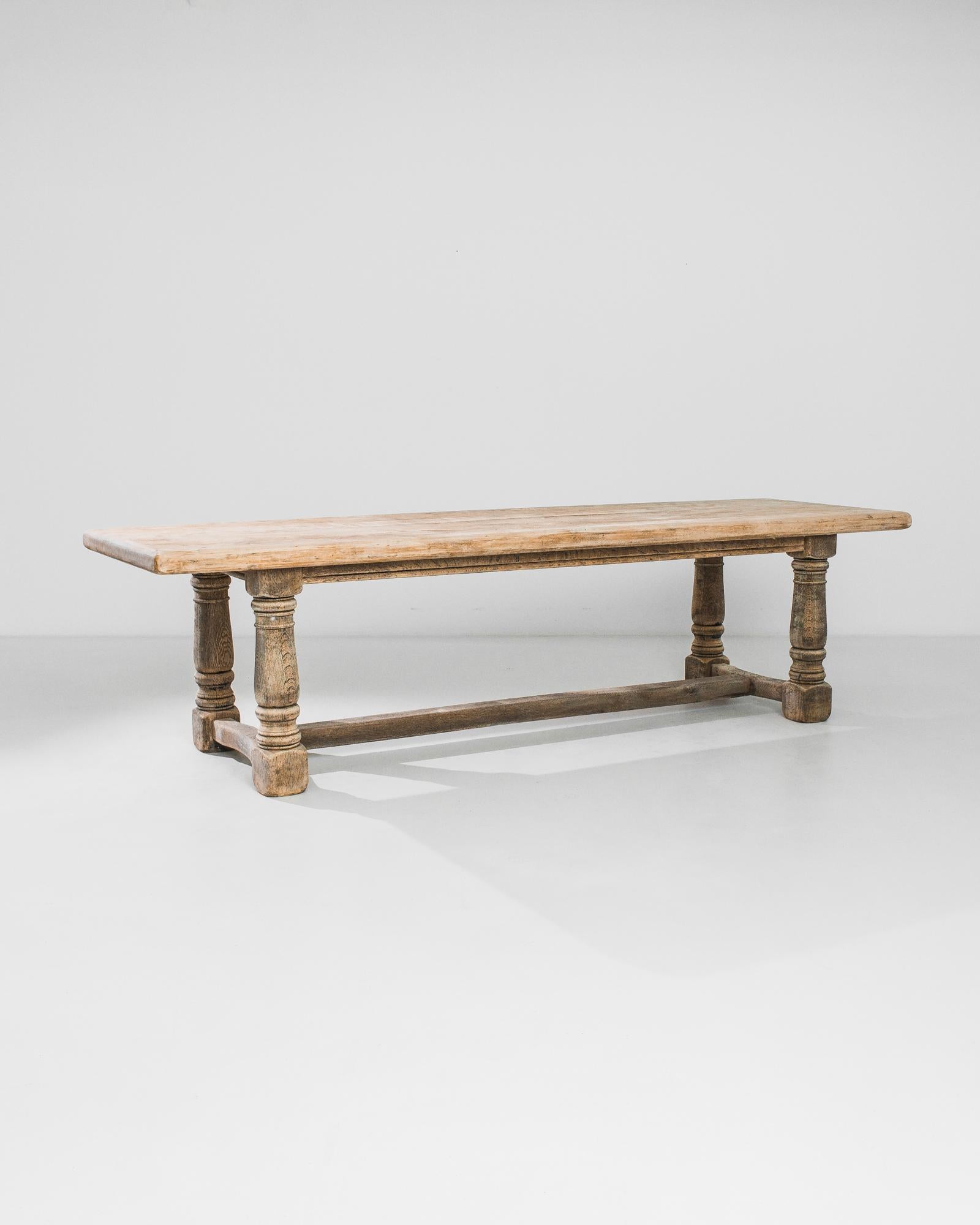 A dining table designed and crafted in Belgium circa 1970. Simple table top crafted out of oak is raised on firm baluster legs. The table’s height —it’s only two and a half feet tall —permits the use of the table as a bench. This curious mid-century