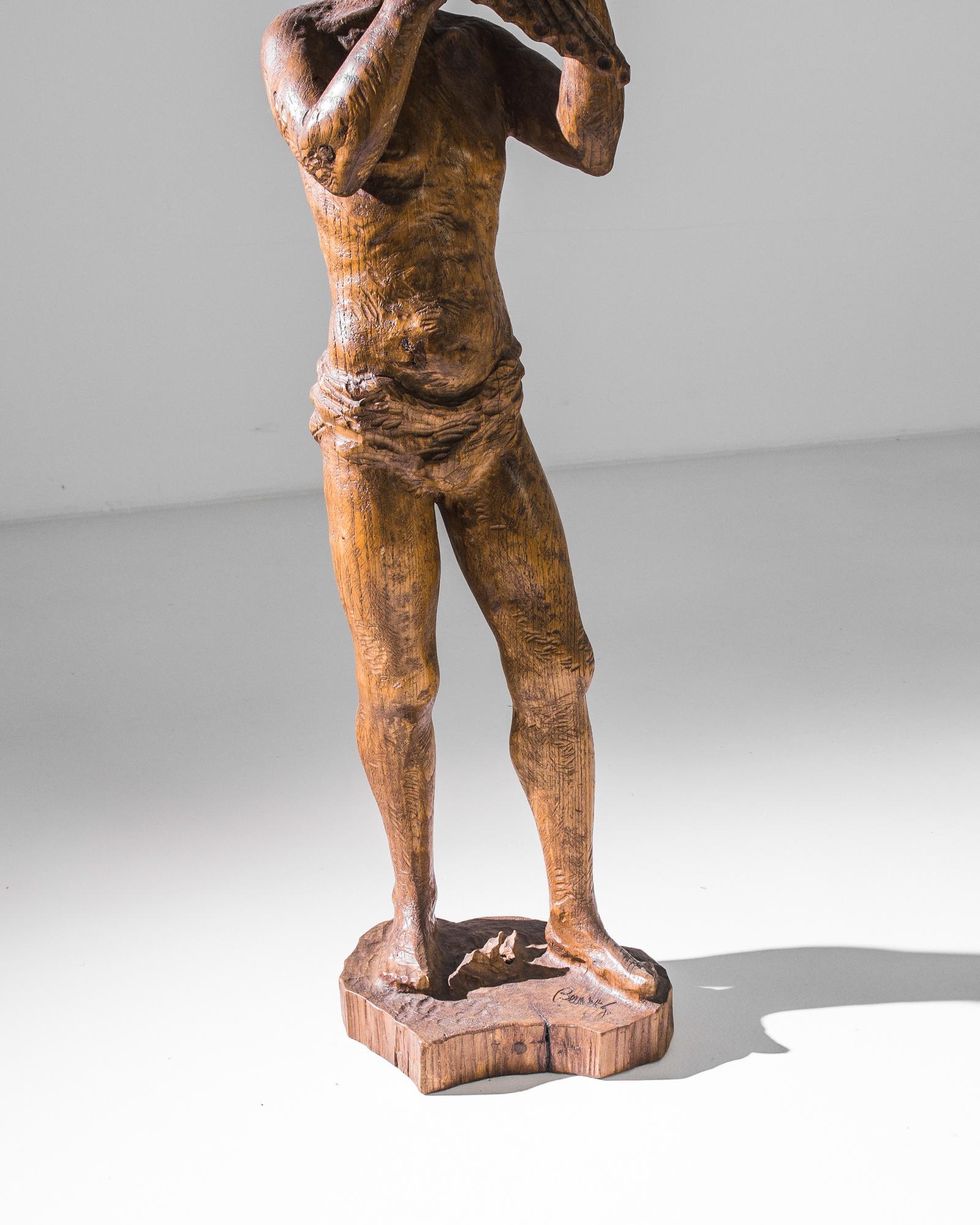 This wooden sculpture with a glossy patina was made in Belgium, circa 1970. It depicts a standing figure playing the pan flute, staring dreamily into the distance. The skillful carving can be appreciated in the details of the character’s hair curls