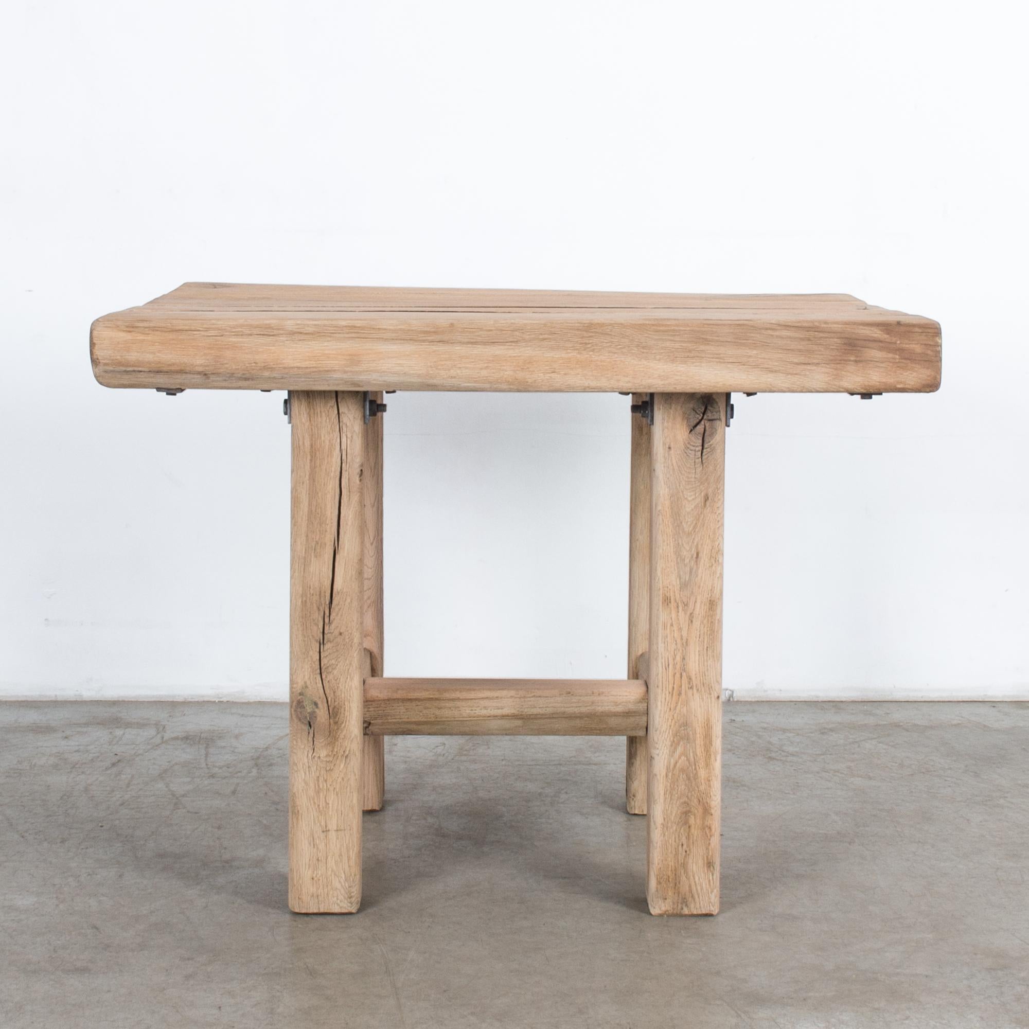 This sturdy and rustic wooden side table was made in Belgium, circa 1970. The table top consists of four panels and is supported on four angular legs with an H-stretcher base. The wood grain rings and cracks add charm and character to this table.