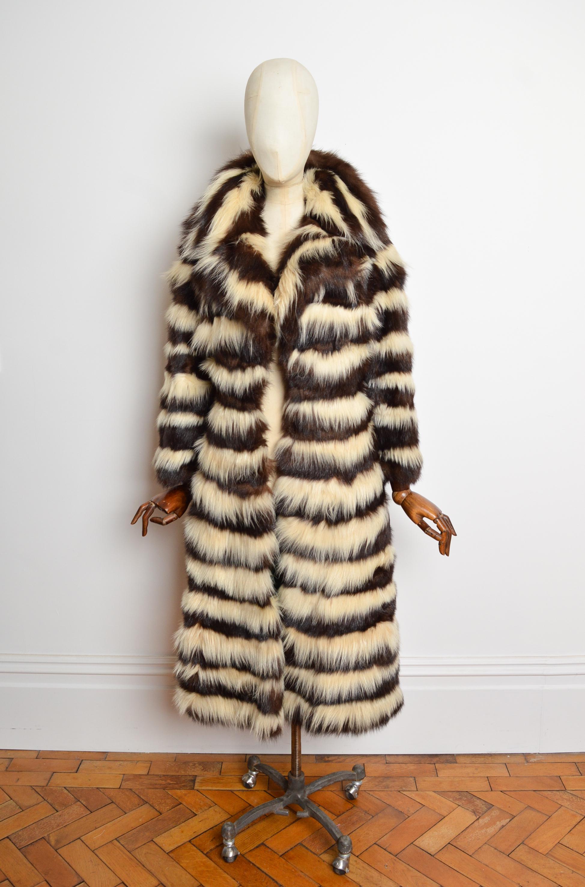 Un extraordinario abrigo de los años 70 del diseñador y peletero estadounidense Ben Kahn. 
Ejemplos similares se encuentran en el Museo Metropolitano de Nueva York. 
Este magnífico abrigo de piel a rayas de felpa viene en marrón chocolate y blanco,