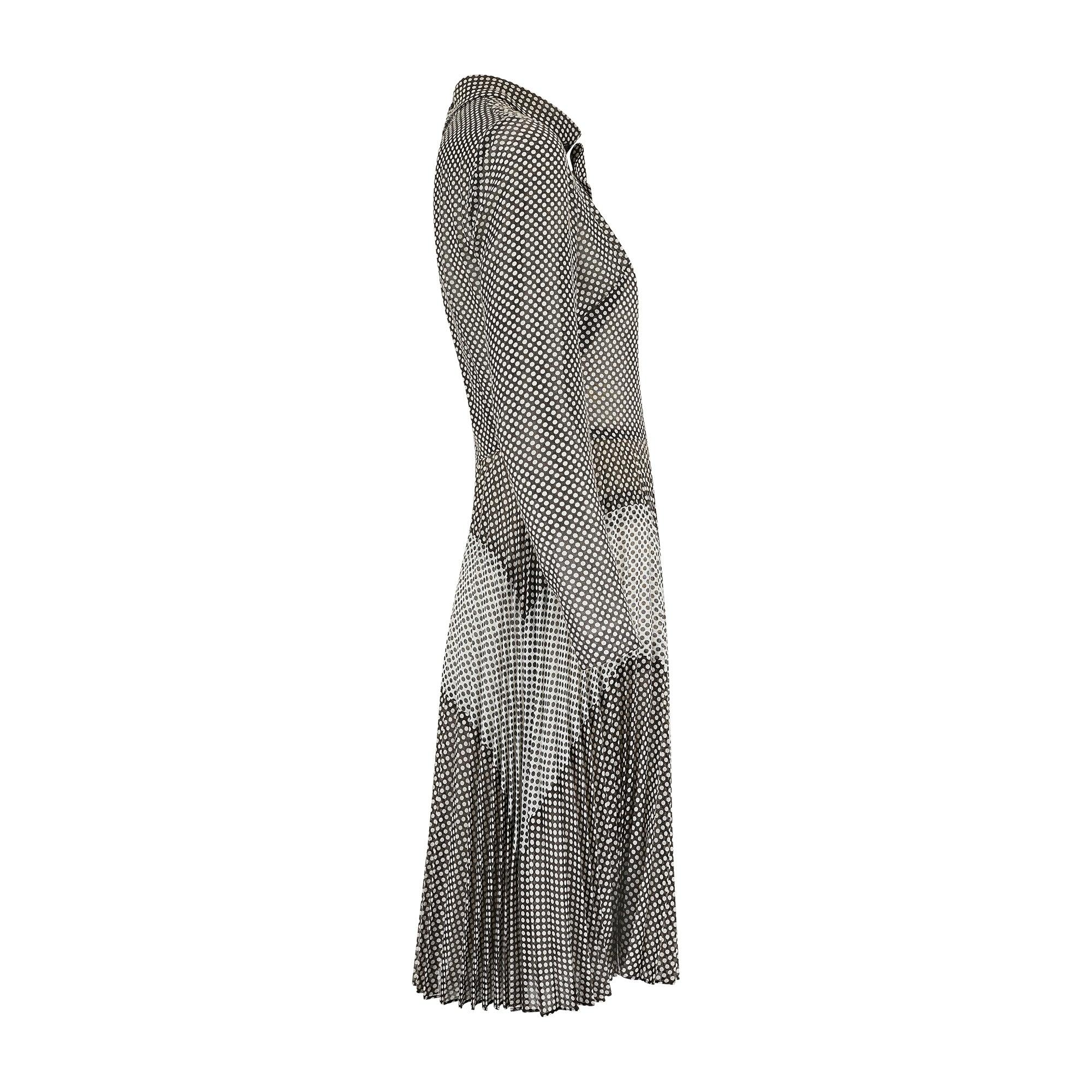 Fabriquée en Angleterre, cette robe Berkertex des années 1970 est confectionnée dans une gaze de coton légère à pois noirs et blancs.  Taillée dans une silhouette à manches longues et à encolure haute, la jupe plissée à volants tombe à la longueur