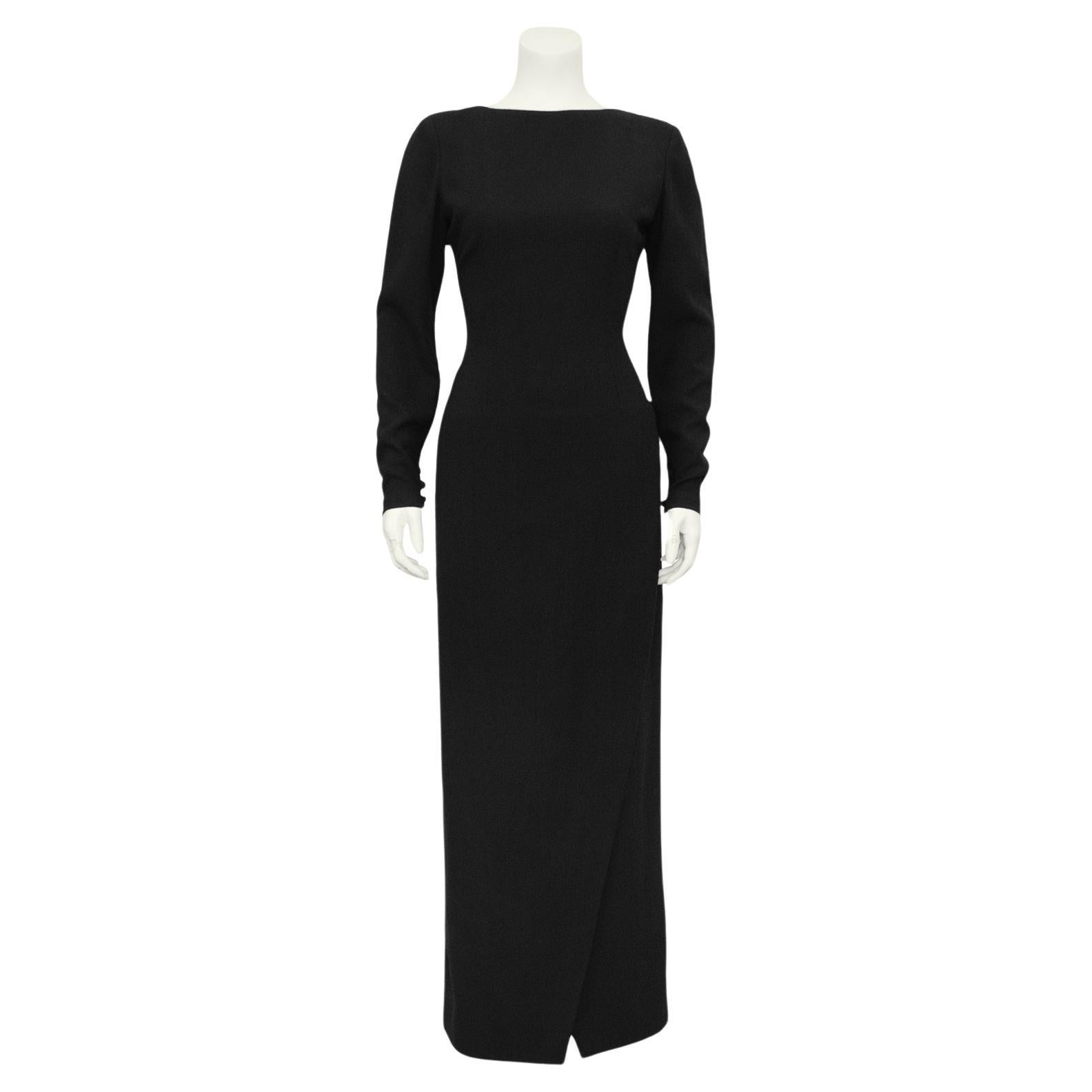 Incredibly chic fall/winter Bill Blass black wool crepe evening gown from the 1970s. Minimal and elegant front with a boat neckline and long sleeves. Fitted through the waist with a floor length wrap style column skirt. The back features a large