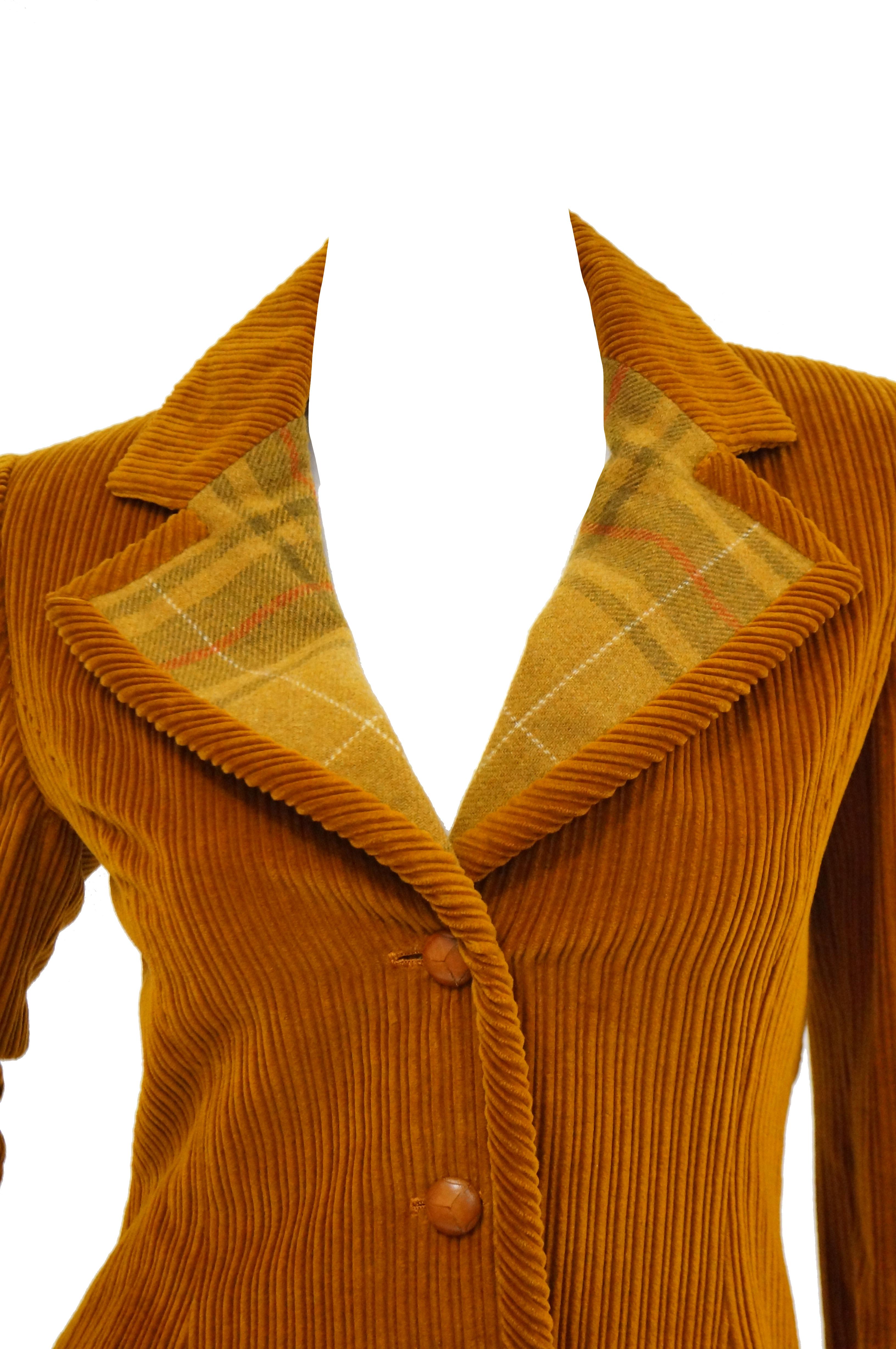 Groovy two piece suit from Bill Blass comprising of very 70s staples like heavy corduroy and golden plaid. The A - line skirt has wide box pleats and is composed of a thick gold, light olive green, and red plaid fabric. The orange corduroy blazer