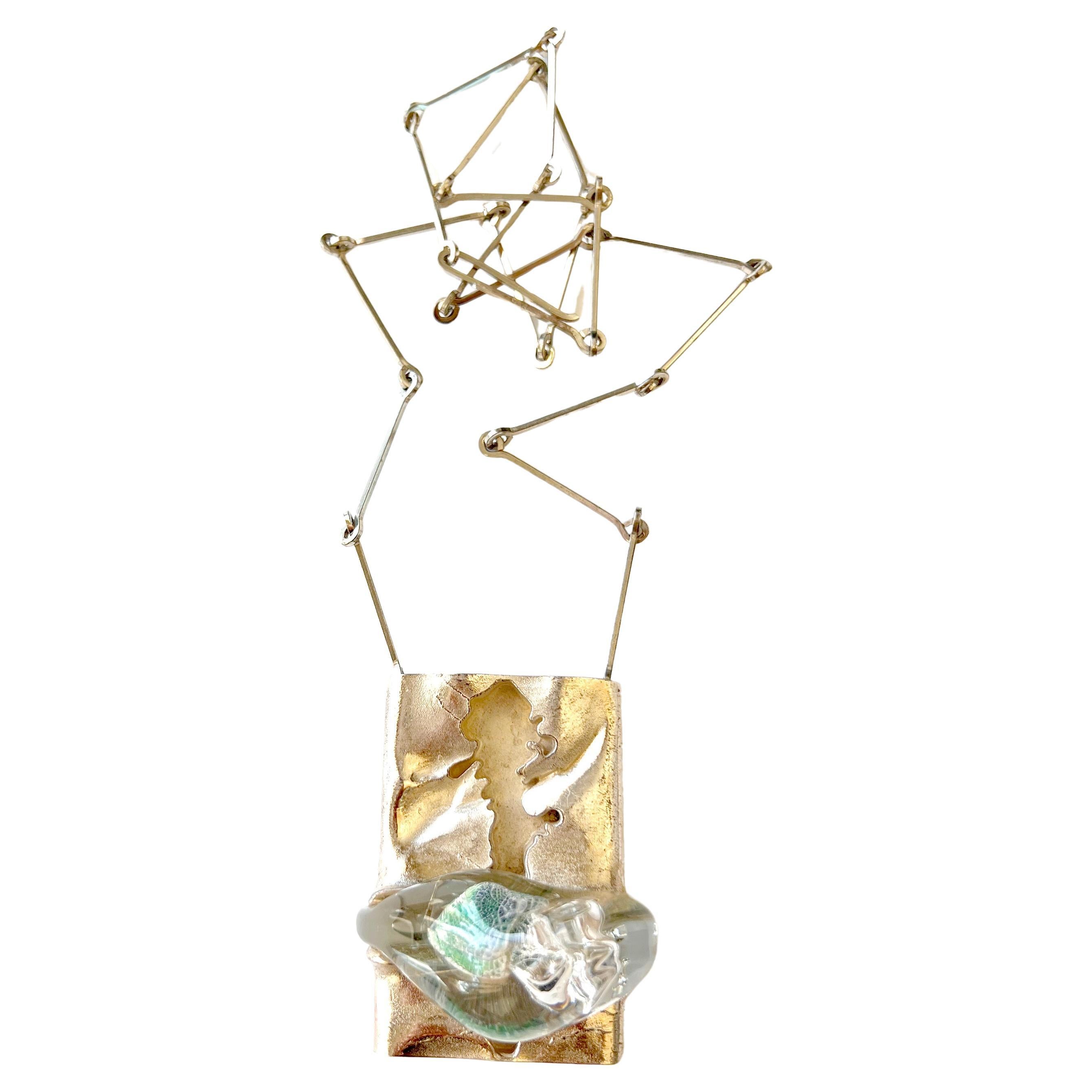 Large scale pendant of green and clear acrylic drop squeezing out of a sterling silver cracked landscape created by Bjorn Weckstrom of Finland.  Pendant measures 2 1/2” tall by 1 3/4” wide and suspends from a sterling silver linked chain that