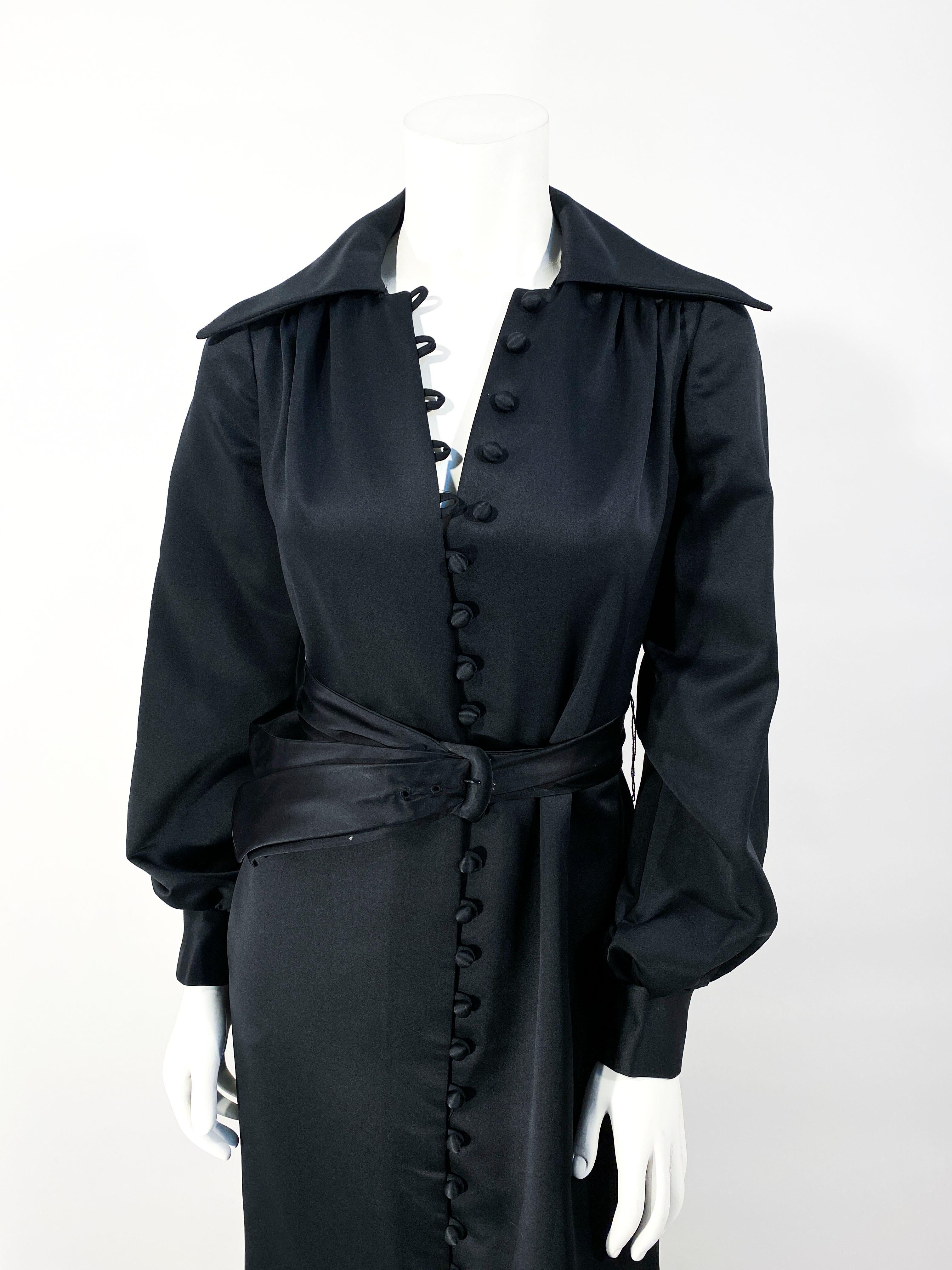 1970s The Eva Gabor Look by Estevez black satin full length dress coat with hand covered buttons, cuffed bishop sleeves. This piece was styled and photographed with a belt that is not included with the purchase of the dress. 
