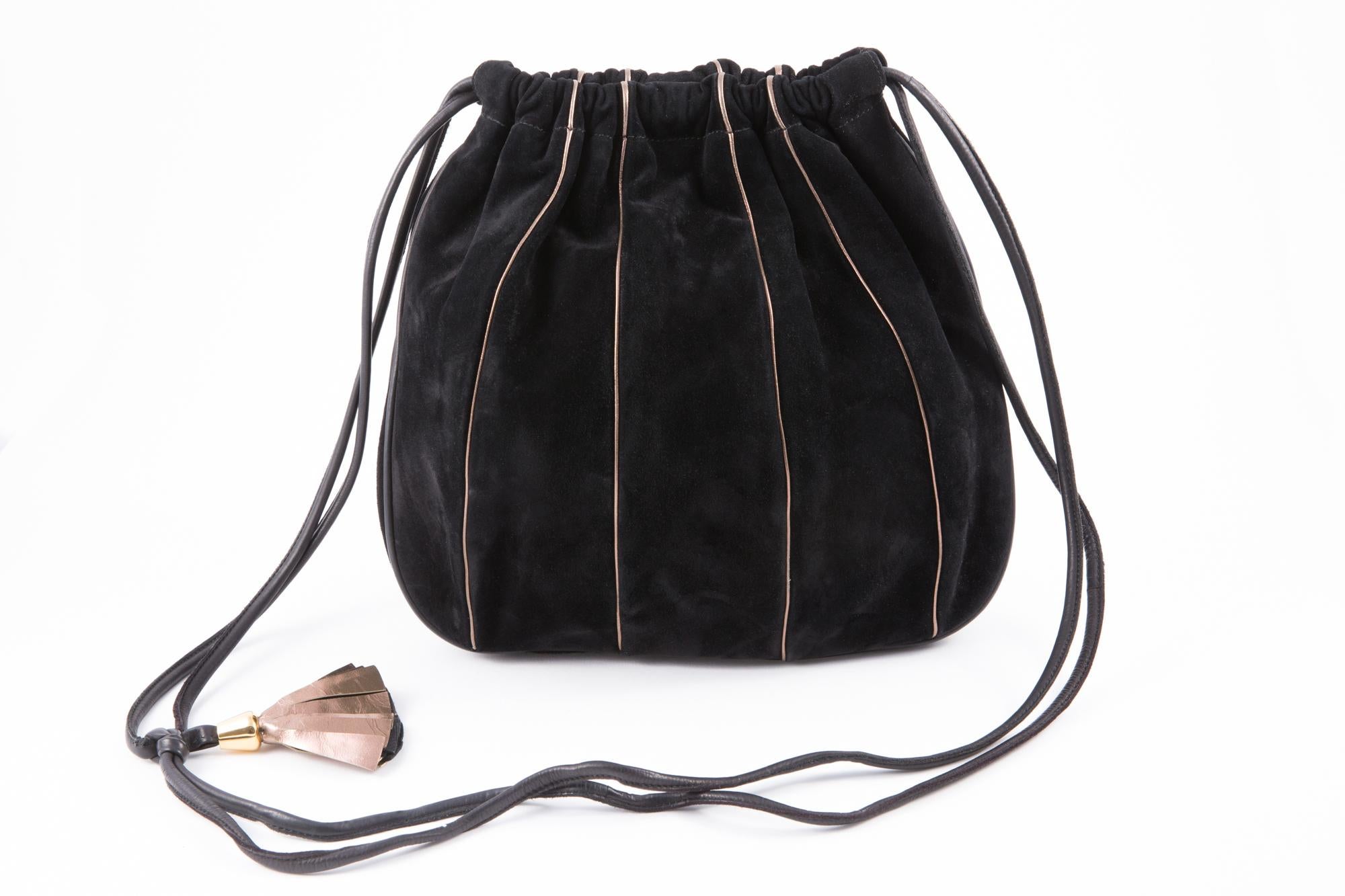 1970s black suede leather shoulder bag featuring gold-tone pipings, a double shoulder leather strap ( 39.3 in. (100 cm), a pinky gold-tone pompon, inside zip pocket, a top snap opening. 
Length 11.4in. (29cm)
Height 11in (28cm)
Depth 1.18in. (3cm)