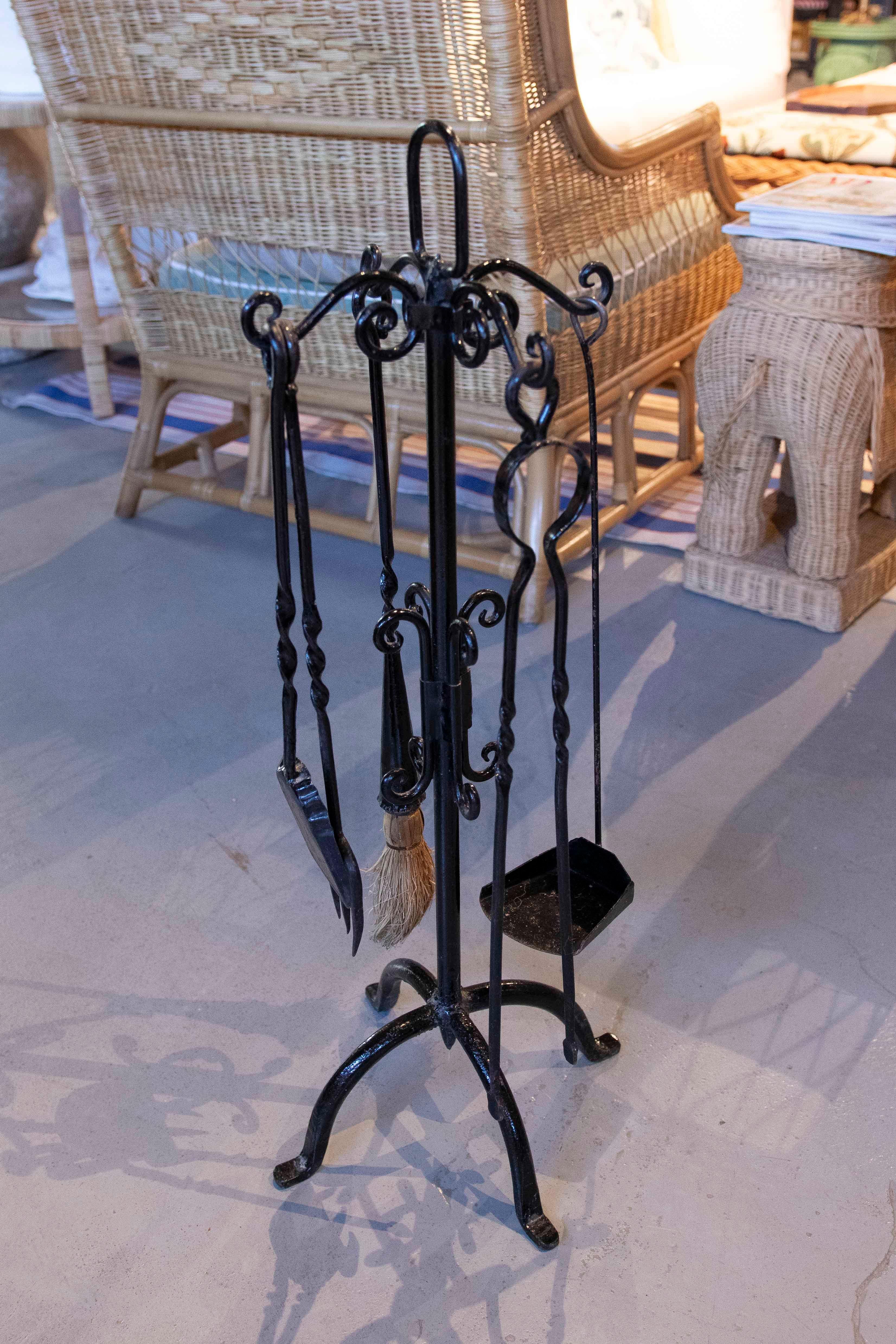 A complete fireplace tool set crafted from wrought iron with a glossy black finish. The set includes a shovel, poker, tongs, and brush, all with classic twisted handles that combine functionality with a handcrafted aesthetic.

The set sits on an
