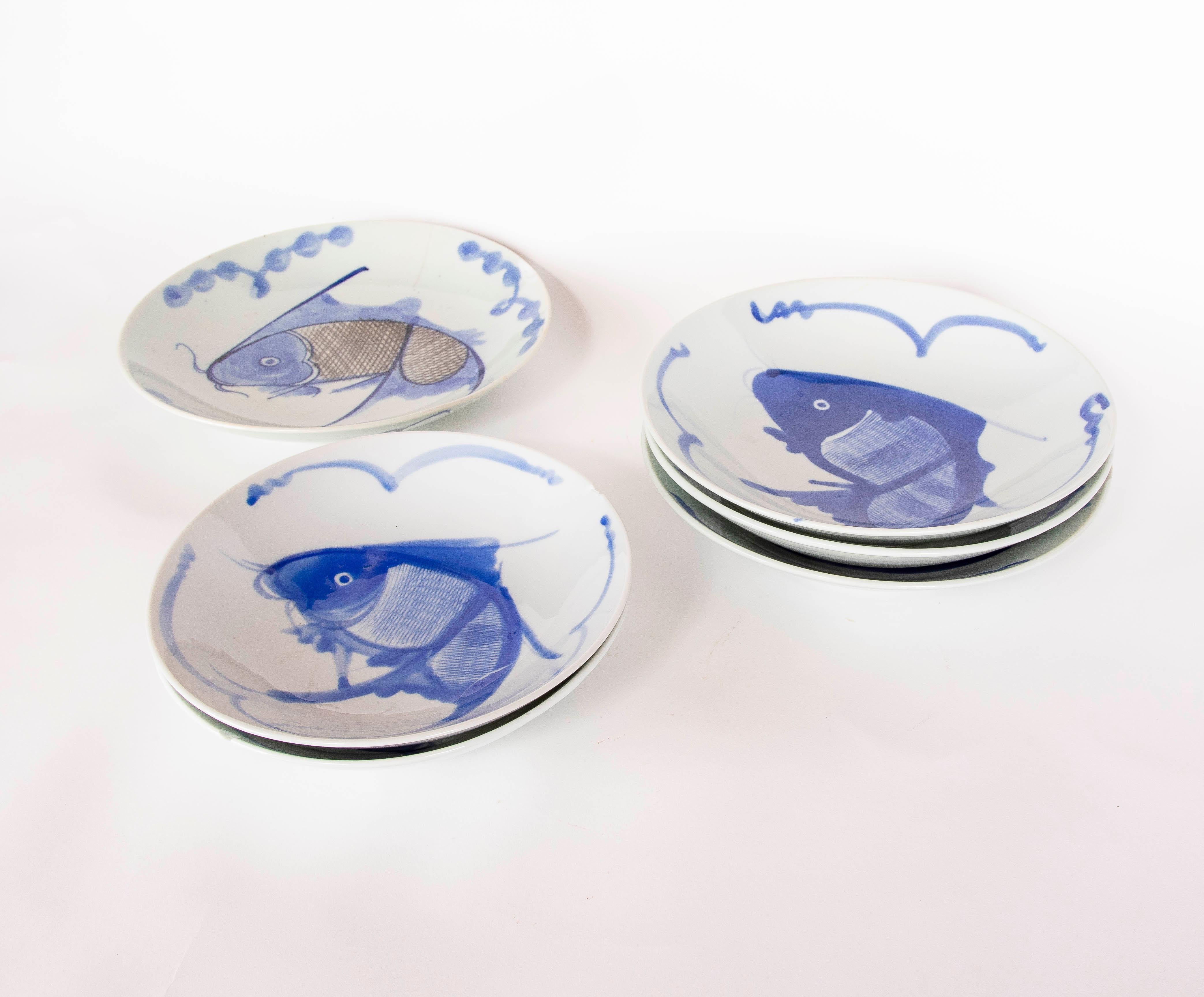 Ensemble de six bols en porcelaine décorés de motifs de poissons peints à la main en bleu cobalt, caractéristiques du style chinois traditionnel. Chaque bol présente un design unique avec des lignes fluides représentant des poissons dans un