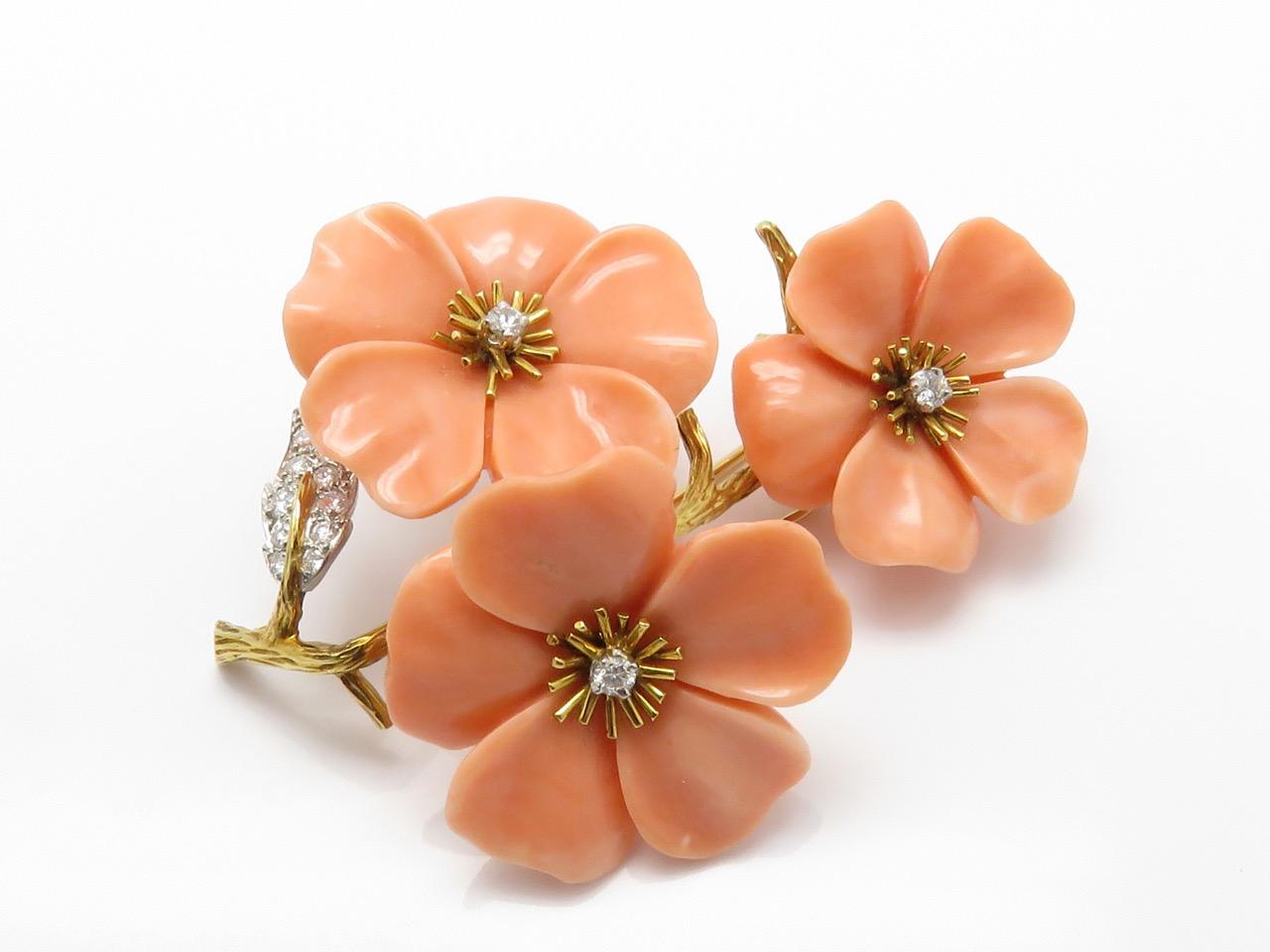 A brooch and a pair of ear clips of flower design , diamonds and coral 