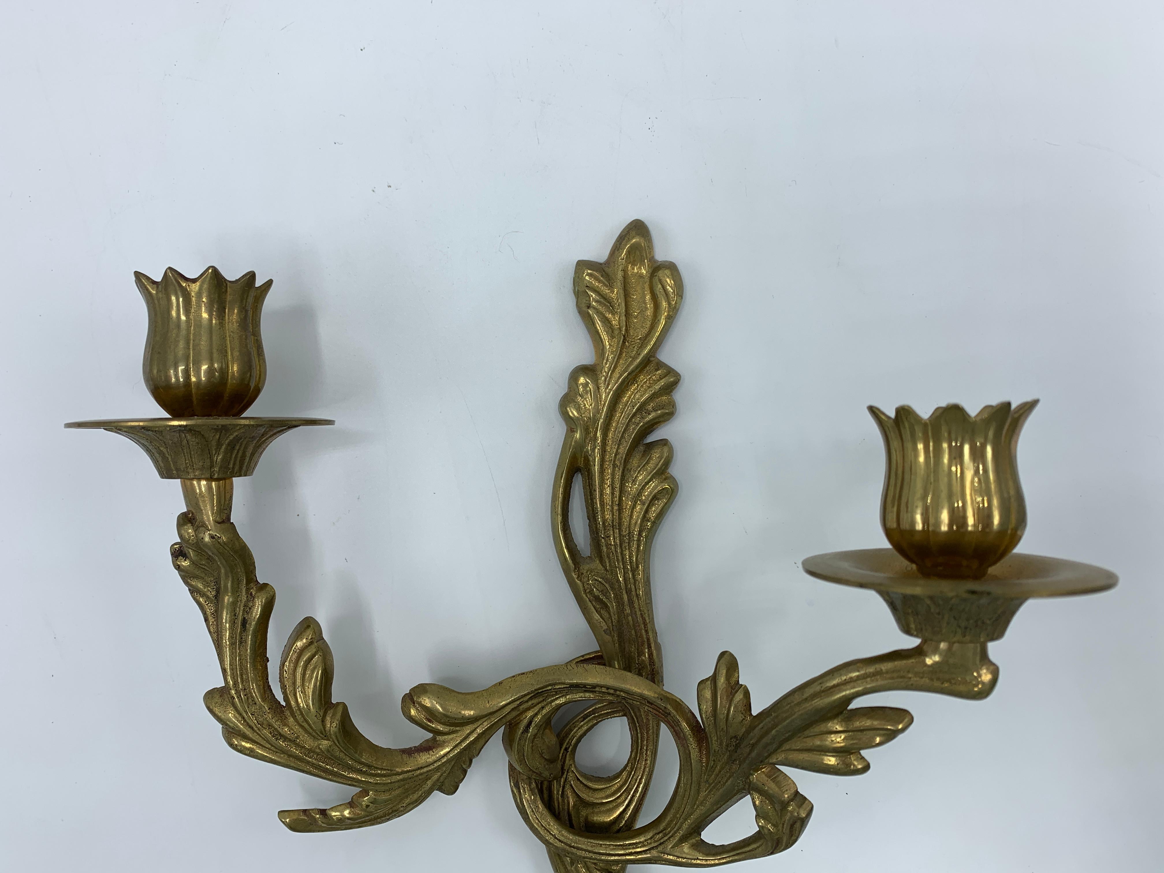 Offered is a pair of 1970s solid-brass, acanthus leaf candlestick wall sconces. Each has a hook on the backside for easy hanging. Attention to detail and craftsmanship were not overlooked when these pieces were created. Lovely detailing all-over.