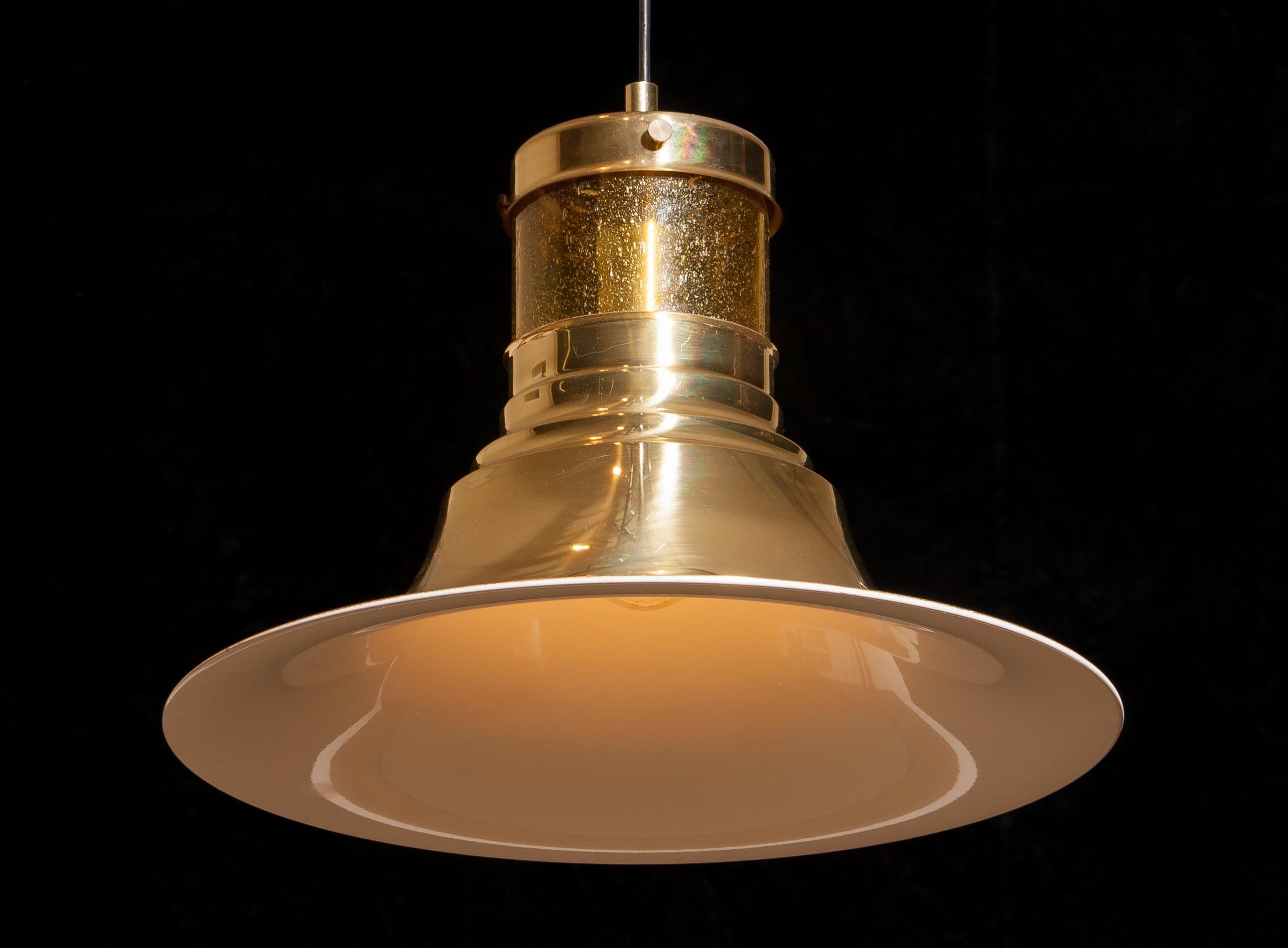 Magnificent pendant designed by Börje Claes for Norellet, Sweden.
This lamp is made of brass with an enamel white inside and a yellow cylinder of glass.
The beautiful shape makes that it gives a wonderful shining.
Period 1970s.
Dimensions: H 32