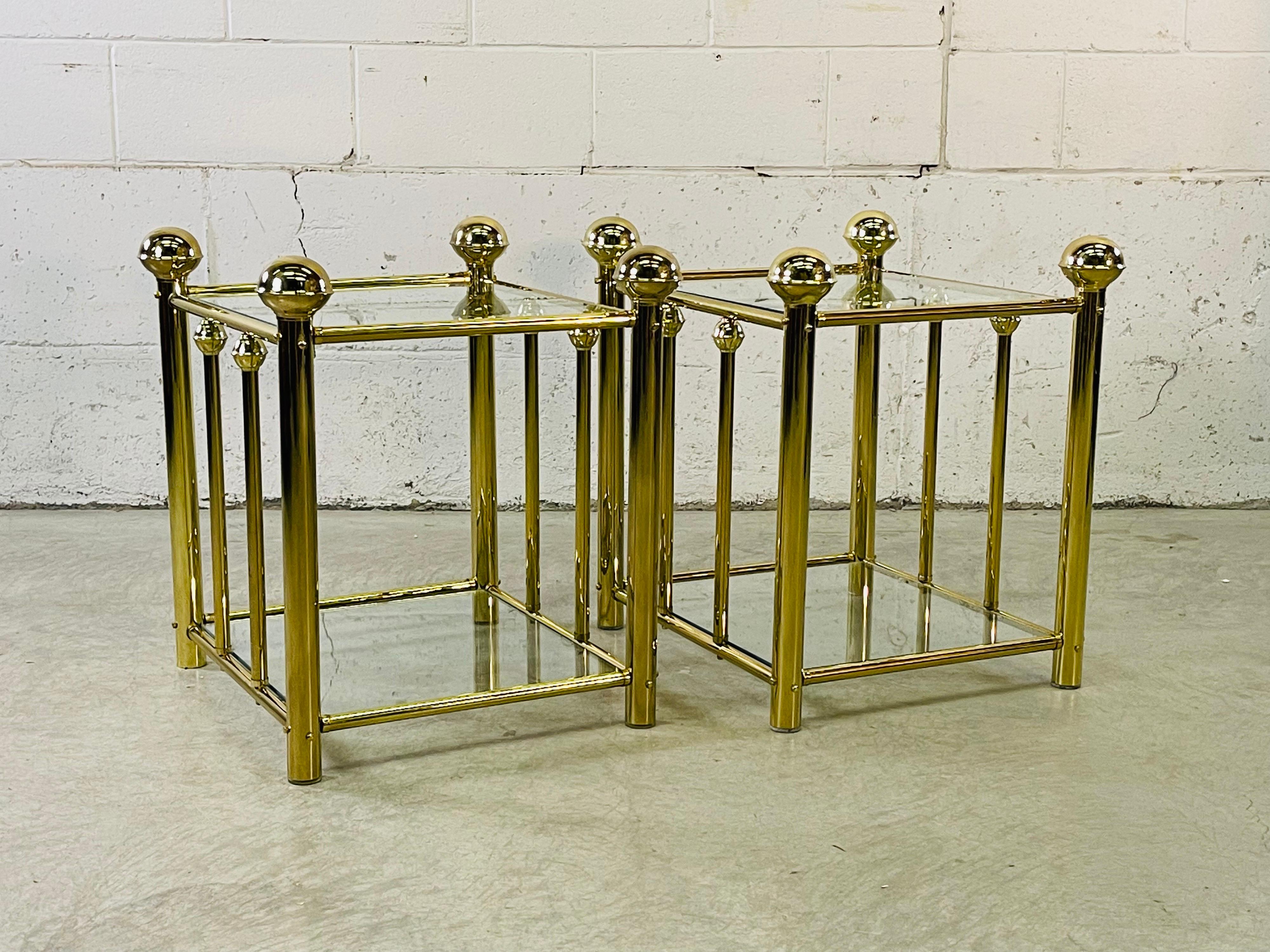 Vintage 1970s pair of brass and glass rectangular side tables. The tables have an additional shelf for storage. There is 17” in height between the shelves. No marks.